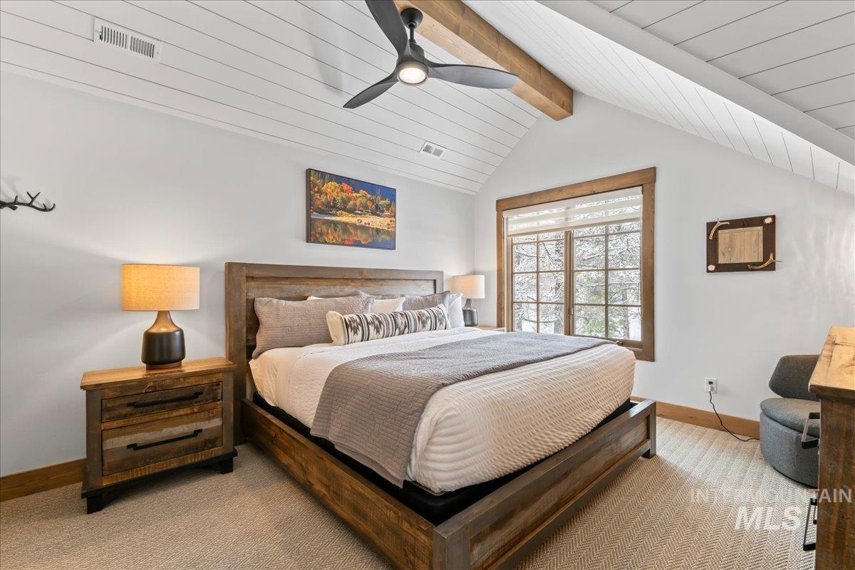 Carpeted bedroom with beamed ceiling and a ceiling fan