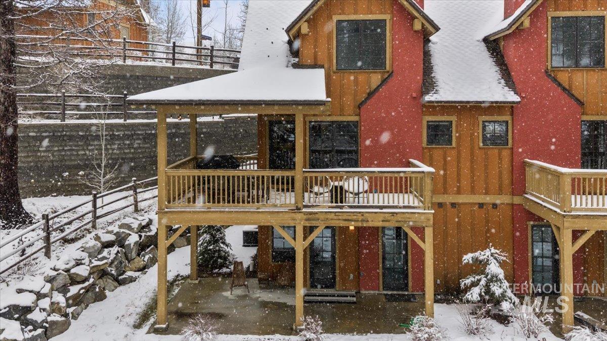 Snow covered rear of property with a patio area