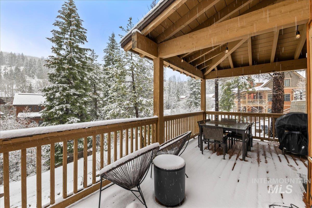 Snow covered deck featuring a grill and outdoor dining area