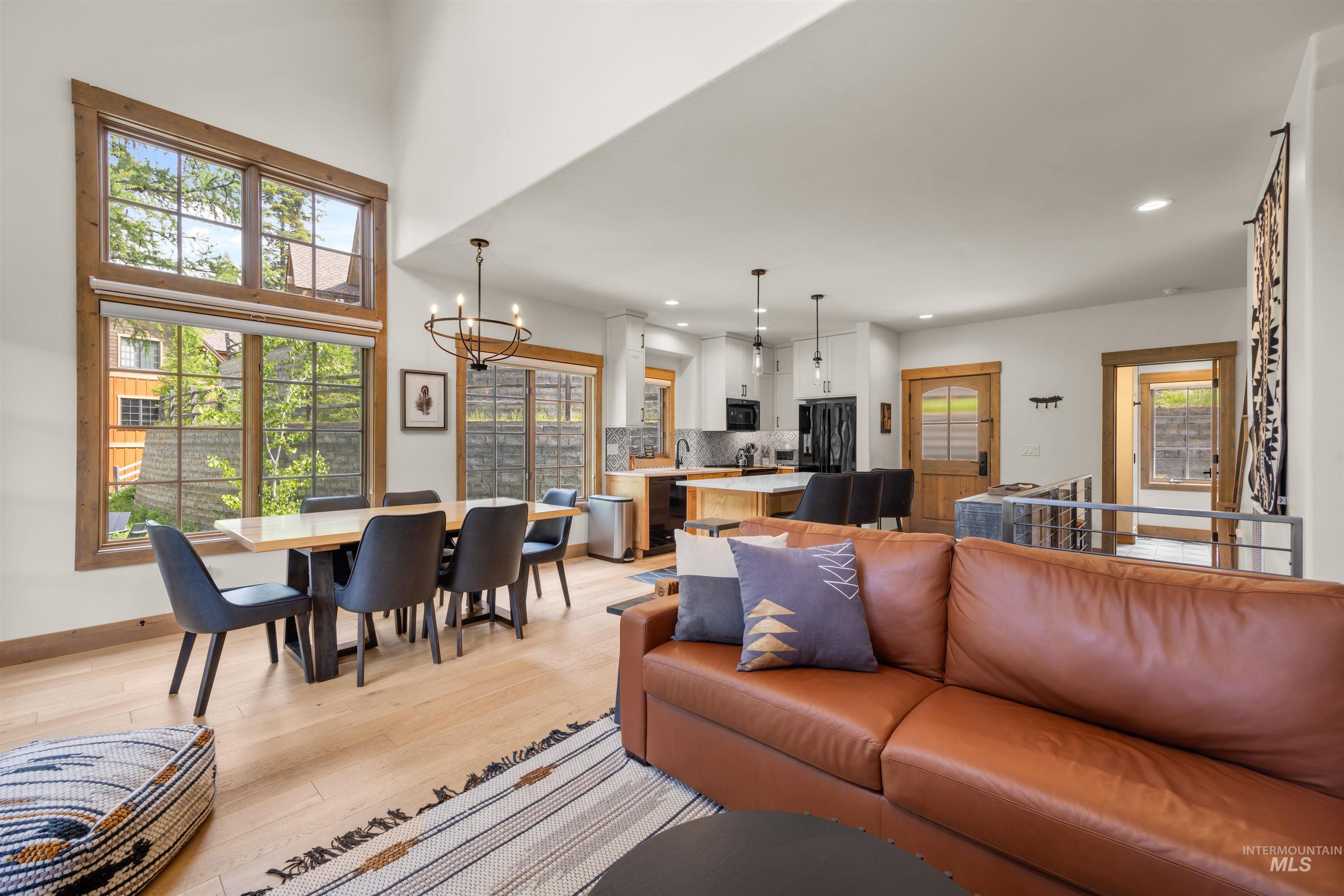 Open-concept living space featuring wood-finish flooring, a vaulted ceiling, and large windows with wood trim