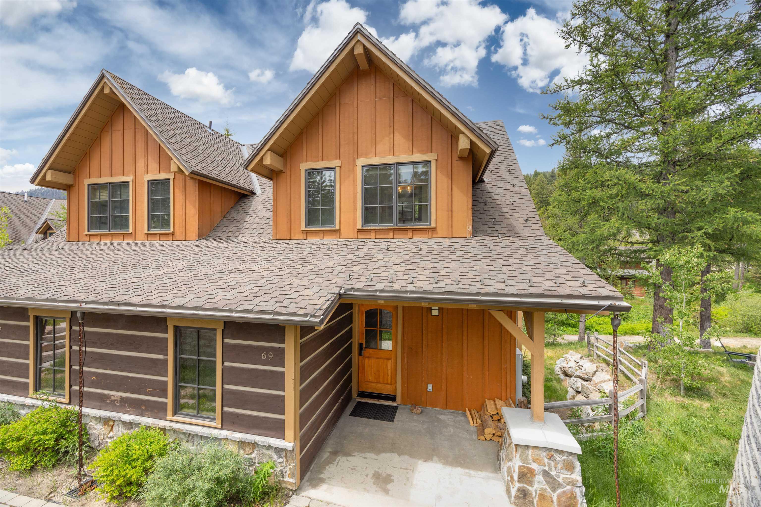 Rustic-inspired exterior featuring log siding, wood paneling, and stone accents
