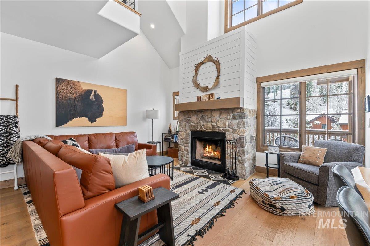 Living area featuring light wood-style floors, a high ceiling, and a fireplace