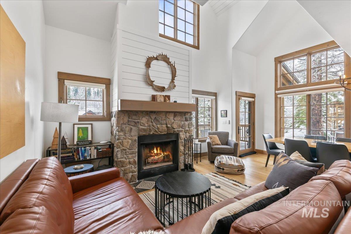Living area featuring a stone fireplace, wood finished floors, and vaulted ceiling