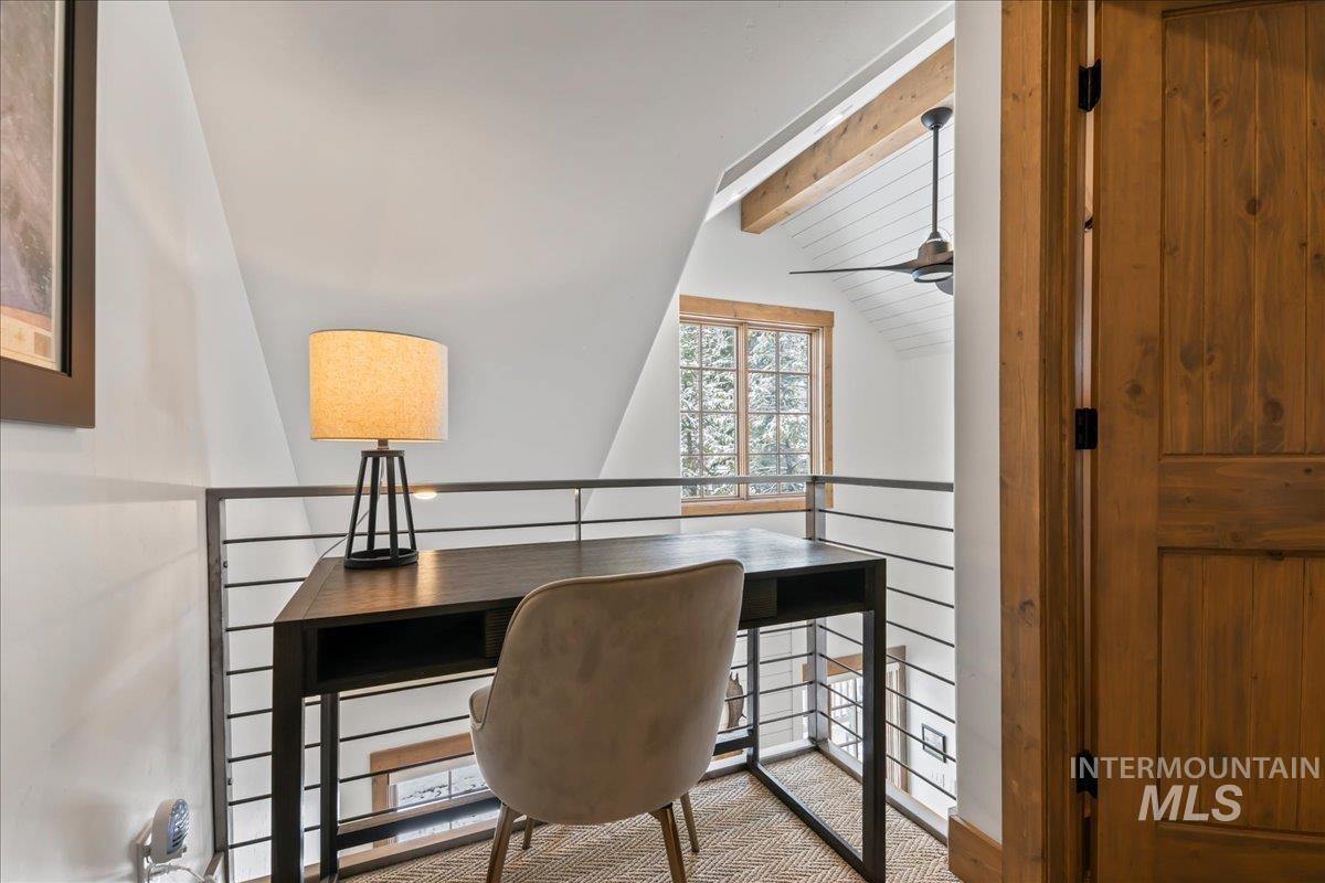 Carpeted home office with vaulted ceiling with beams and ceiling fan