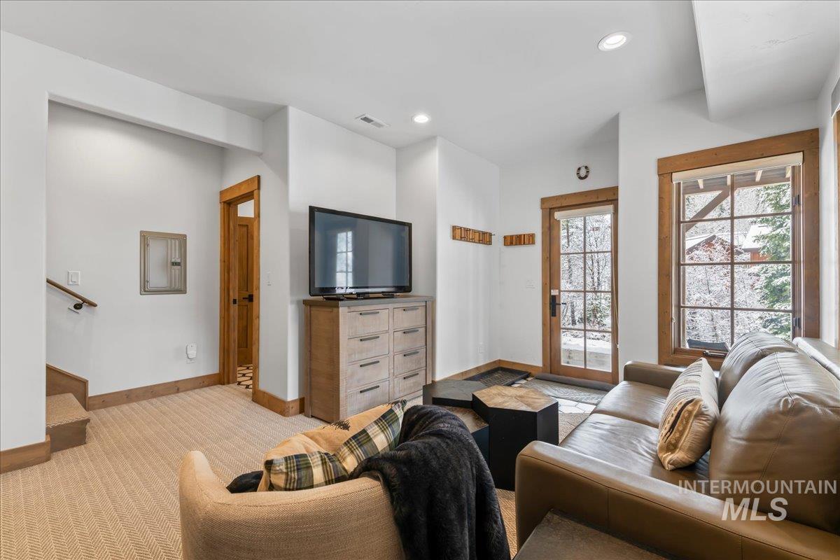 Living area with light carpet, electric panel, and recessed lighting