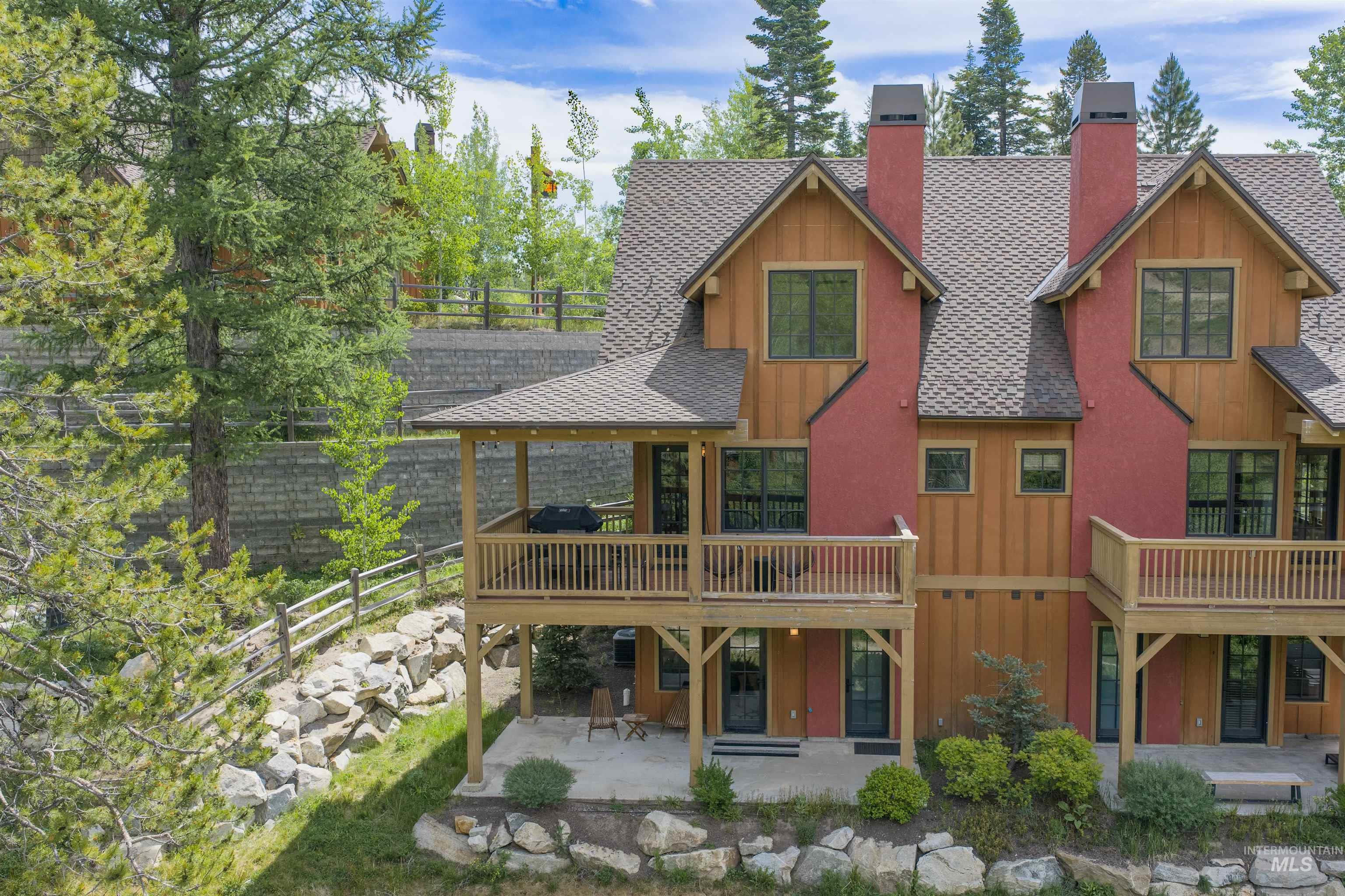 Multi-level exterior featuring wood siding, red accent panels, and multiple covered balconies