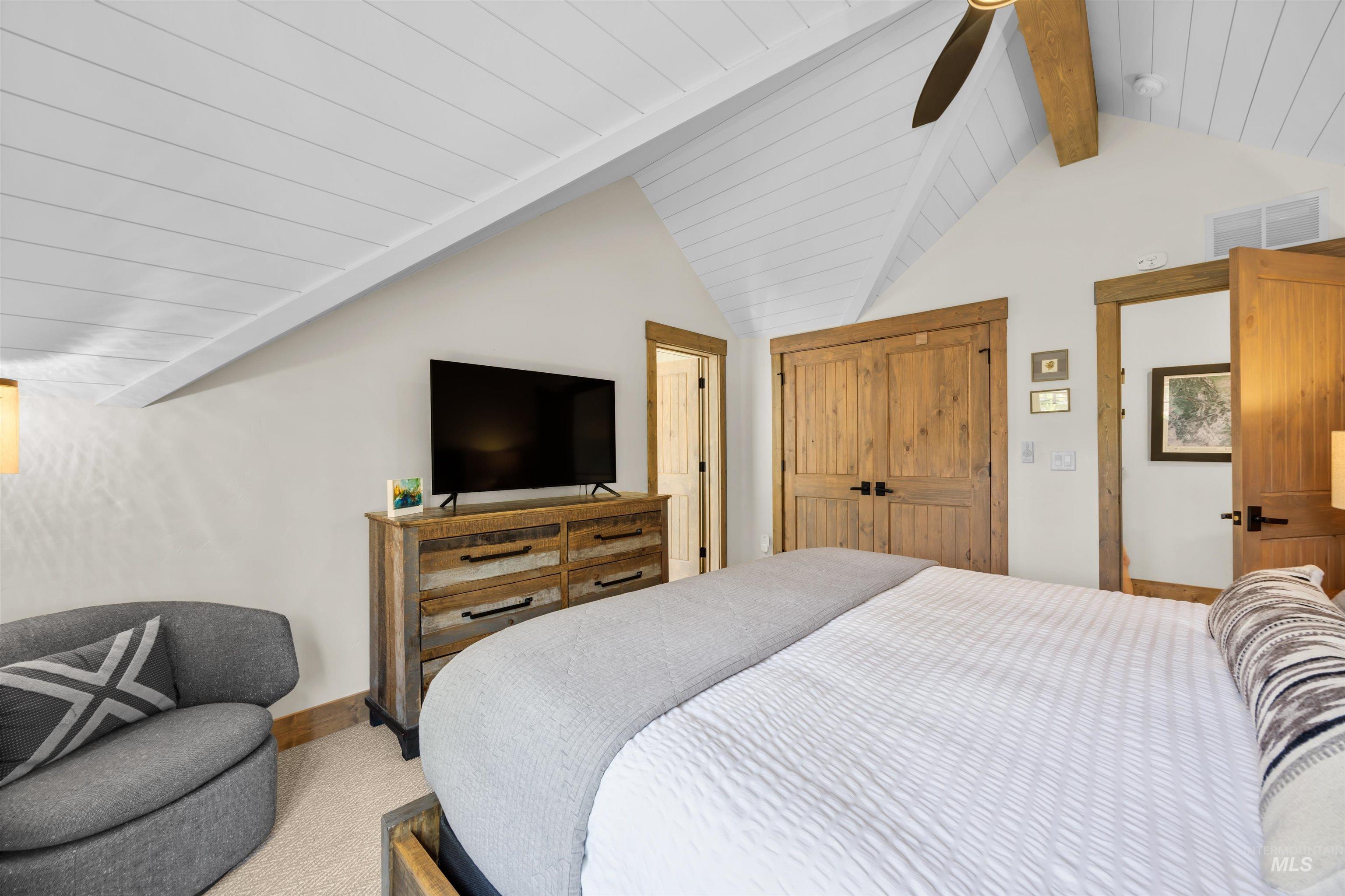 Vaulted ceiling with white plank finish and exposed wood beam
