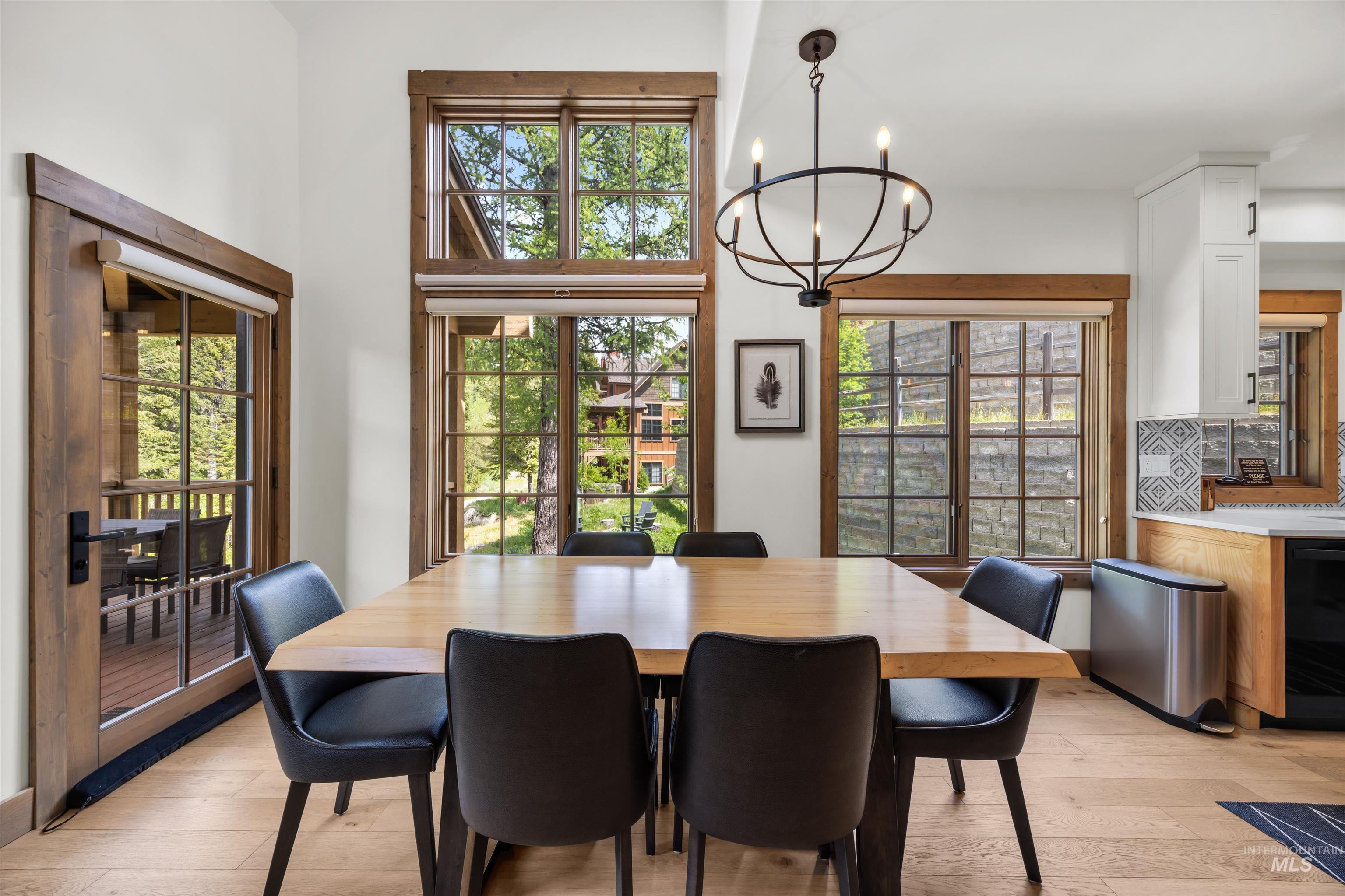 Dining area with wood-finish flooring, a contemporary chandelier, and a large window array