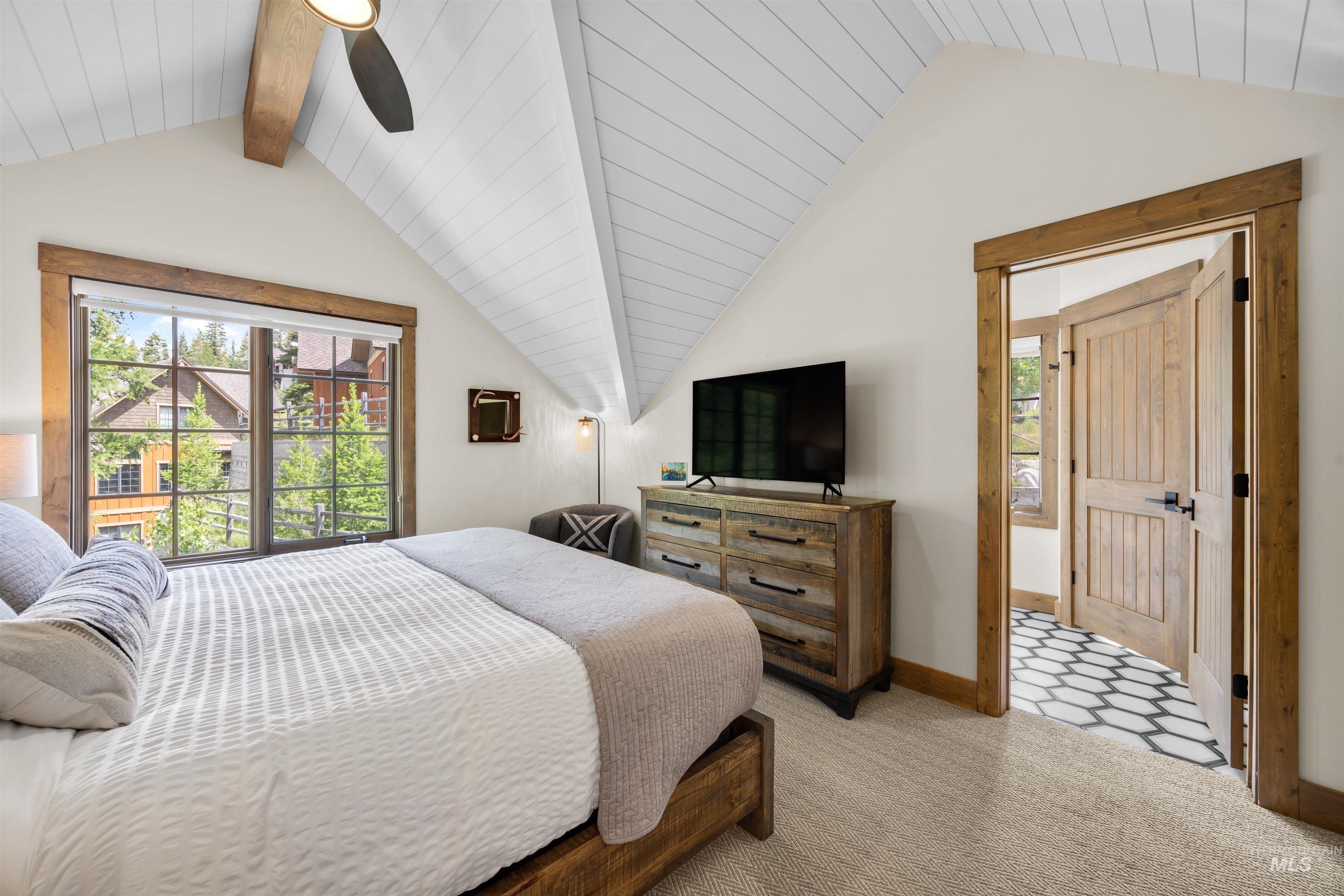 Bedroom featuring an angled shiplap ceiling, wood-trimmed windows, a ceiling fan, and carpet flooring
