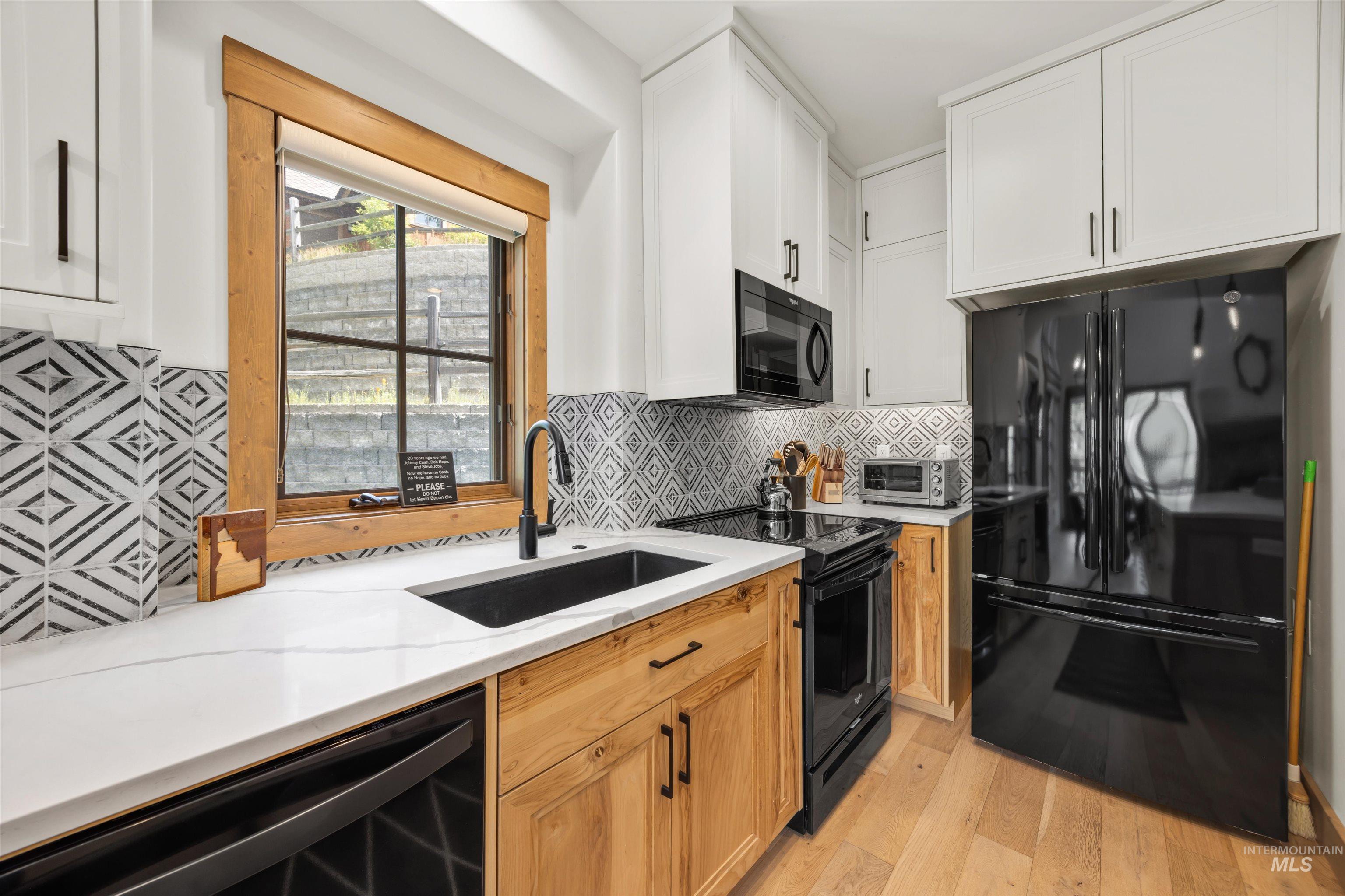 Kitchen featuring white upper cabinetry, wood-finish lower cabinetry, and black hardware