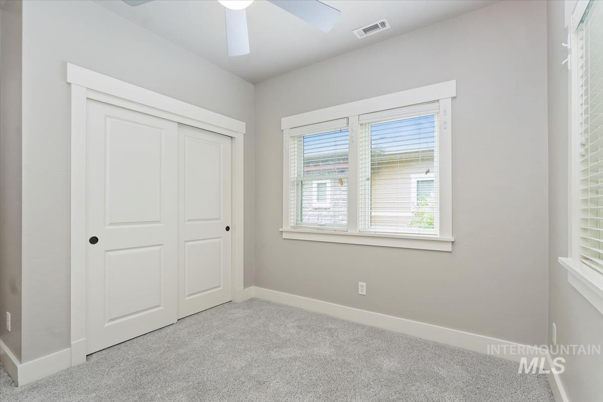Unfurnished bedroom featuring carpet, a closet, and a ceiling fan