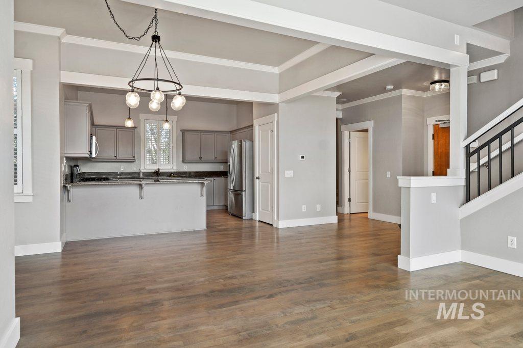 Unfurnished living room featuring crown molding, dark wood-type flooring, and stairs