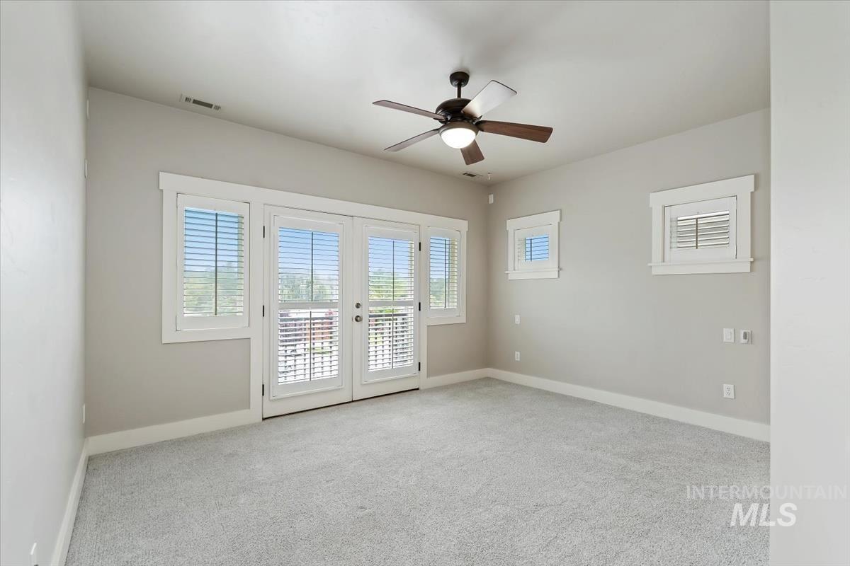 Spare room featuring healthy amount of natural light, french doors, light carpet, and ceiling fan