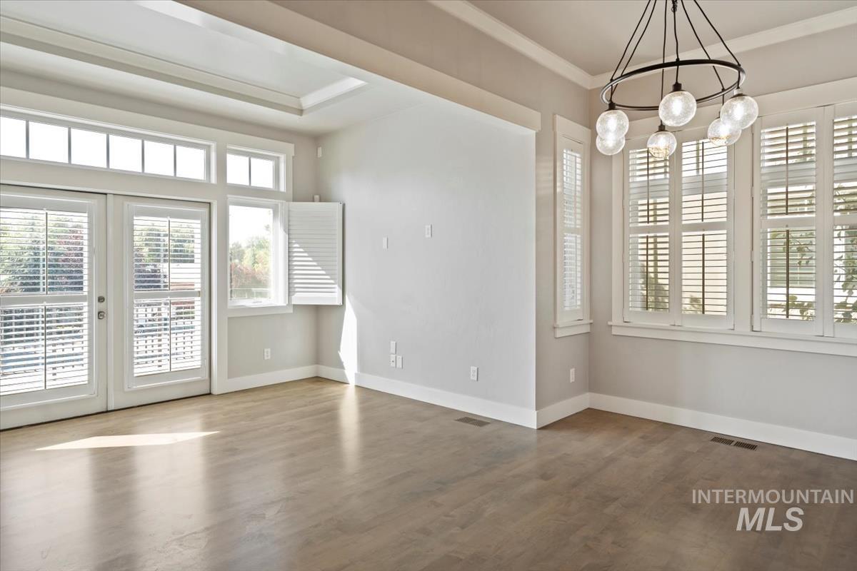 Unfurnished dining area with french doors, wood finished floors, ornamental molding, and a chandelier