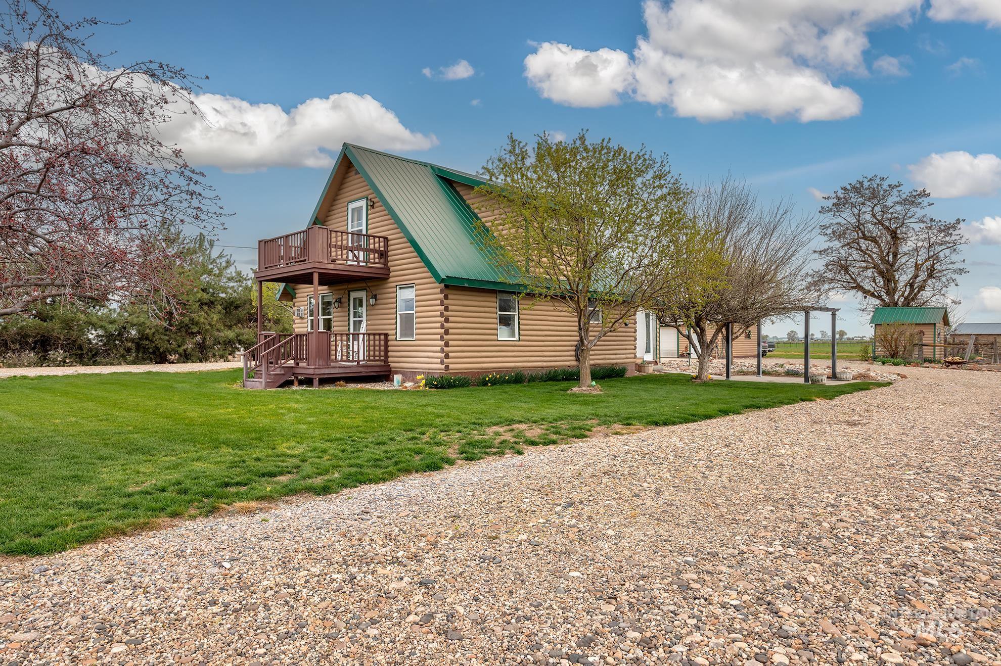 View of side of home featuring a metal roof, log siding, a yard, a deck, and driveway