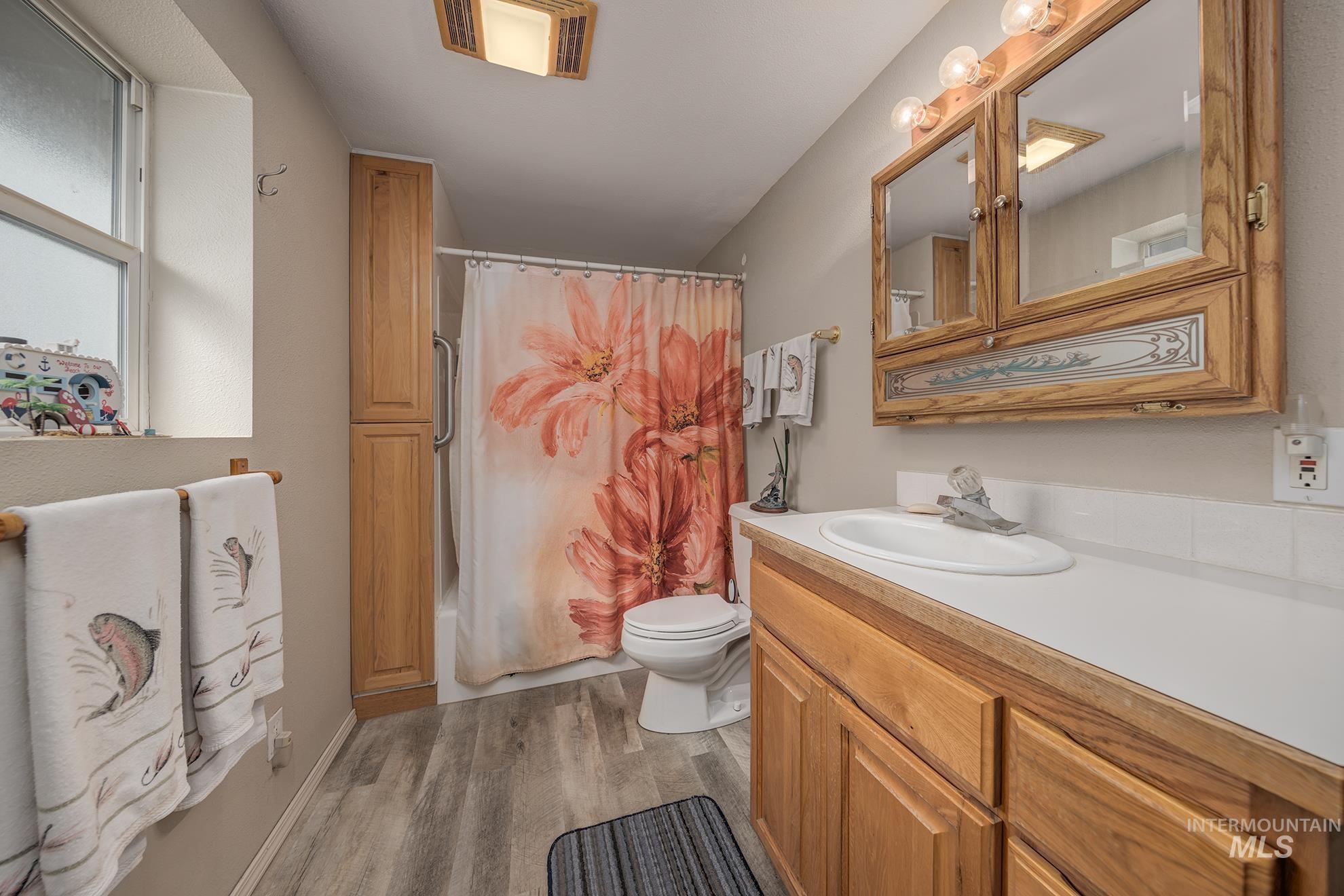 Bathroom with vanity, dark wood finished floors, and shower / bathtub combination with curtain