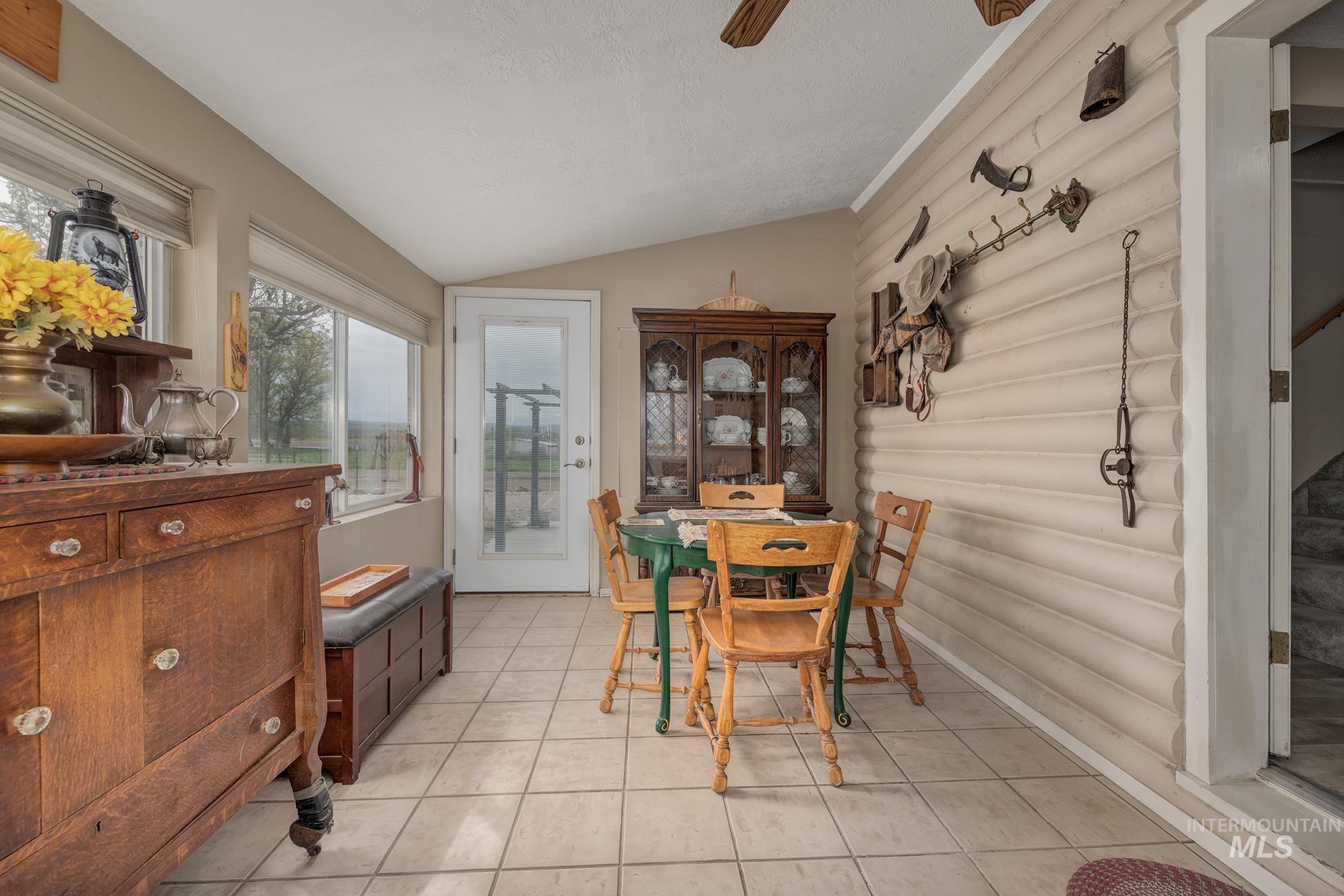 Dining space featuring vaulted ceiling, a ceiling fan, and light tile patterned flooring