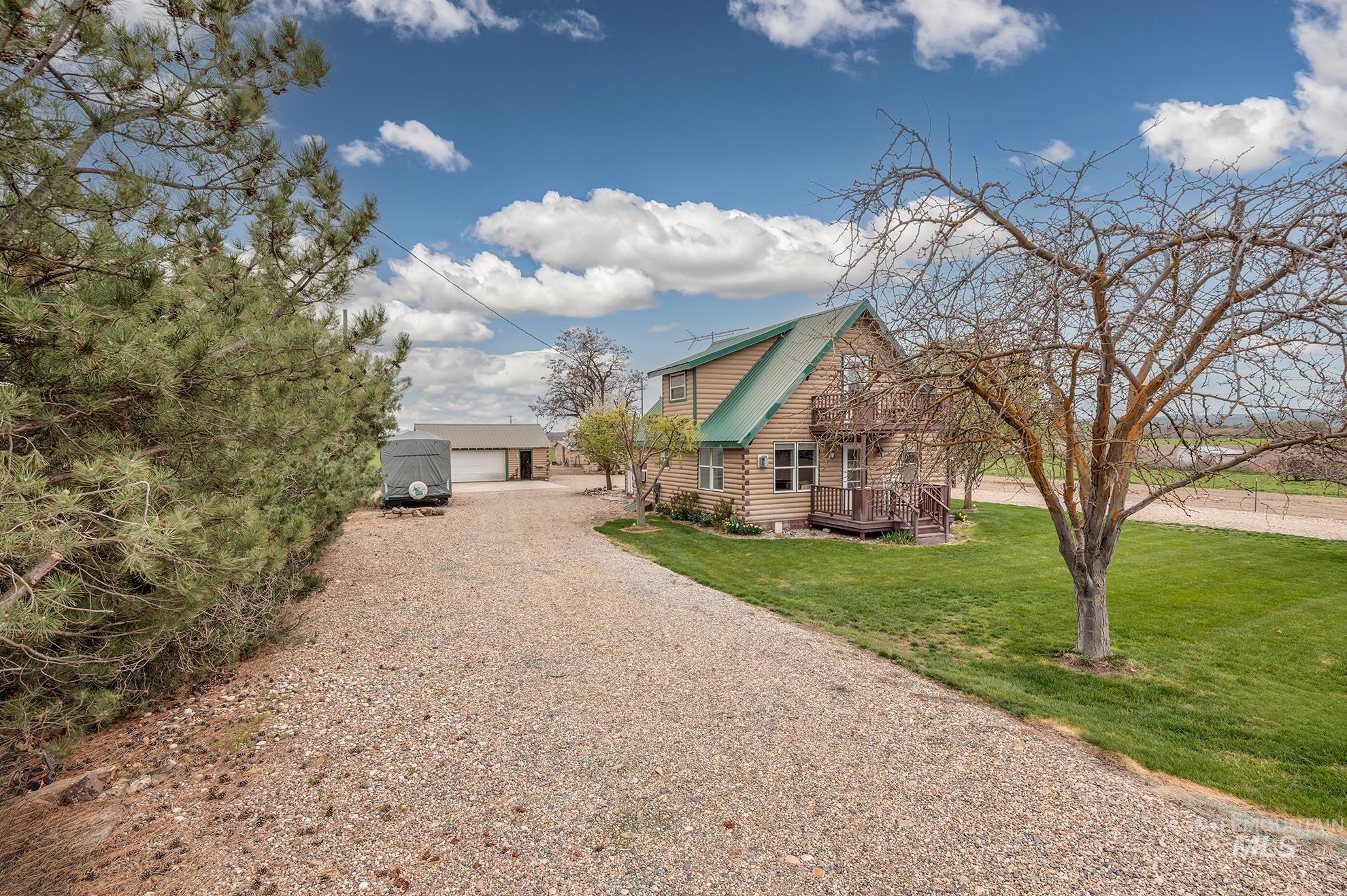 View of front of house featuring an outdoor structure, log siding, a front lawn, a metal roof, and a detached garage