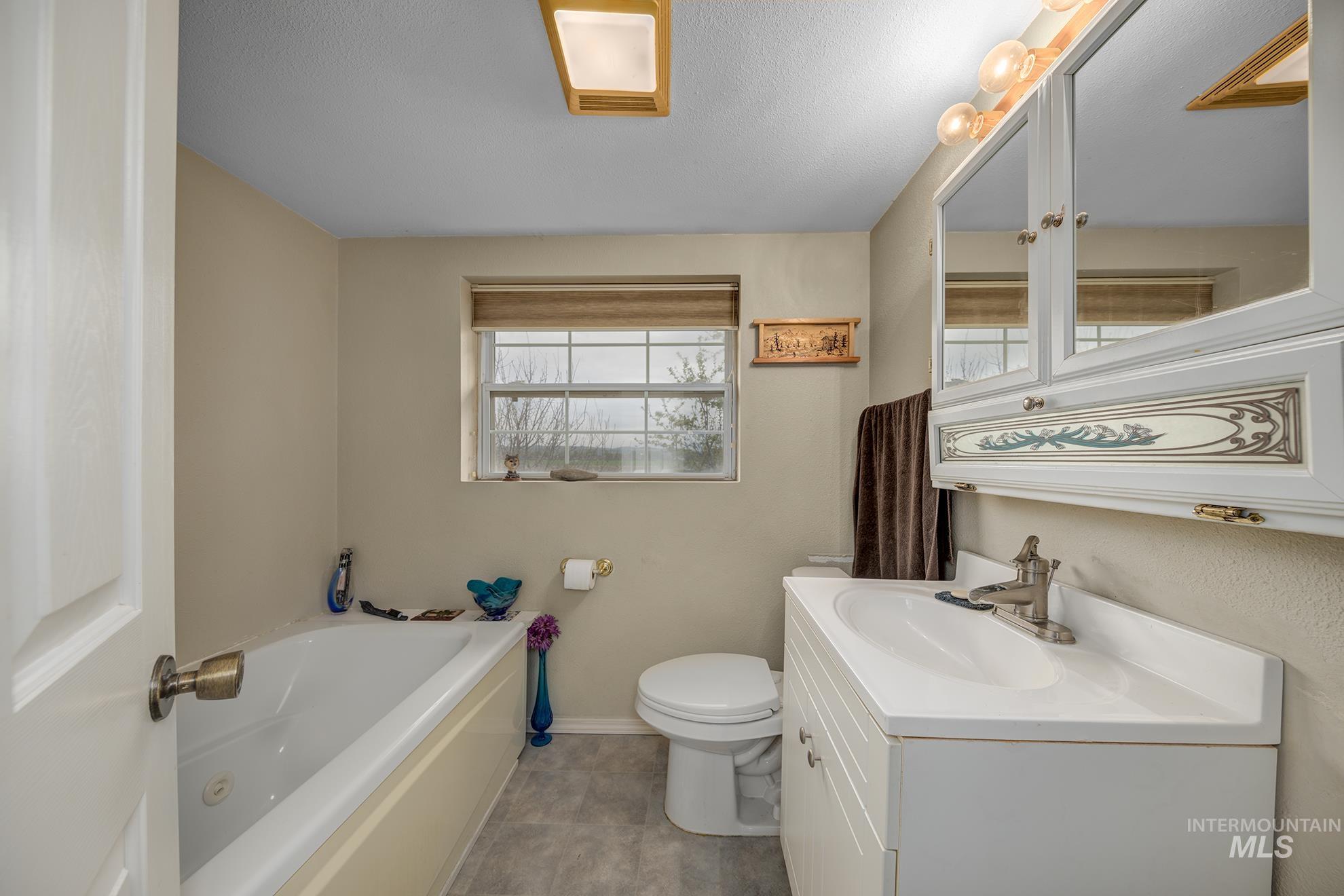 Bathroom featuring a bath, vanity, and a textured ceiling