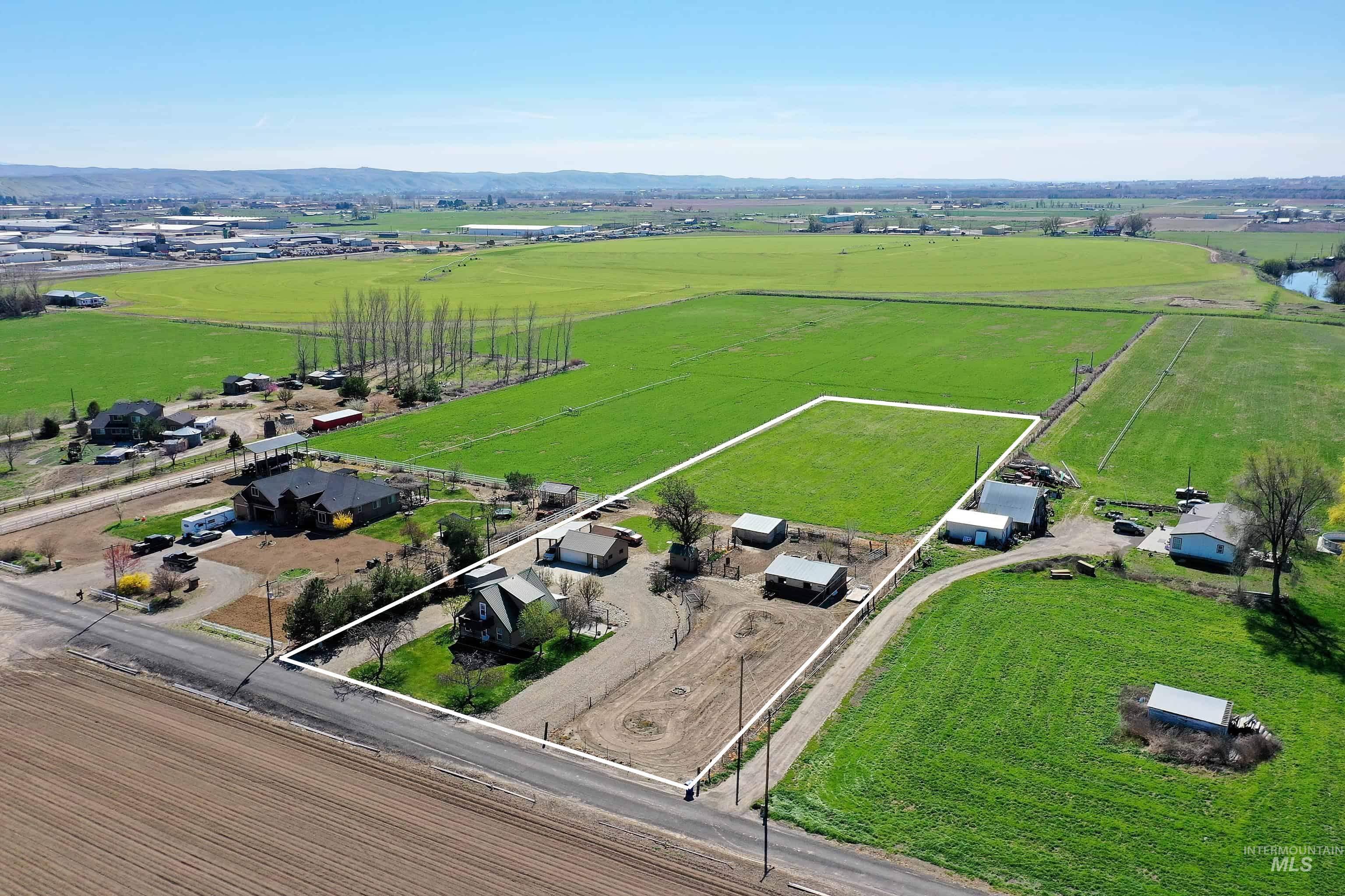 Aerial view of sparsely populated area featuring property parcel outlined, mountains, and abundant farmland