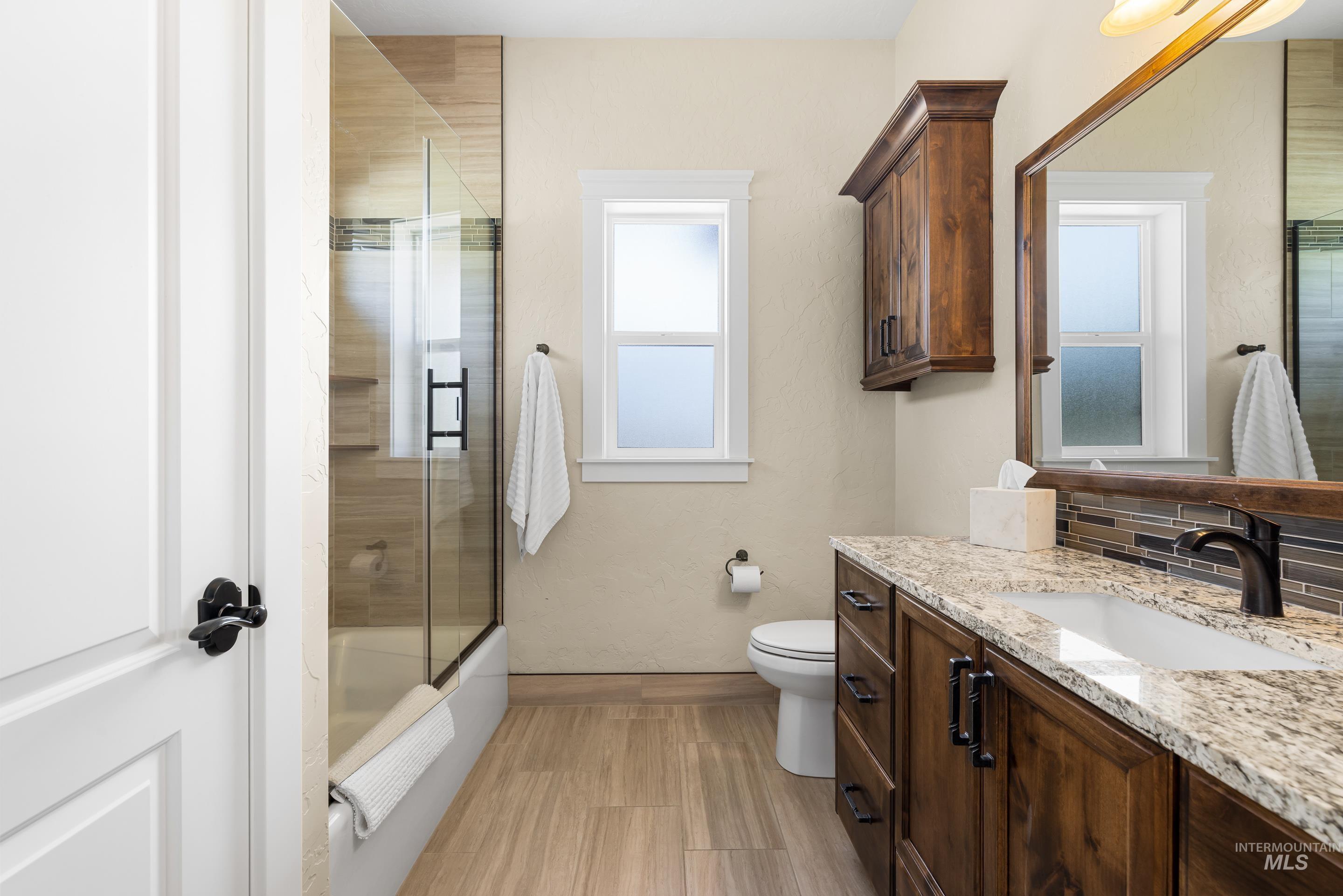 Bathroom with vanity, combined bath / shower with glass door, backsplash, and wood finished floors