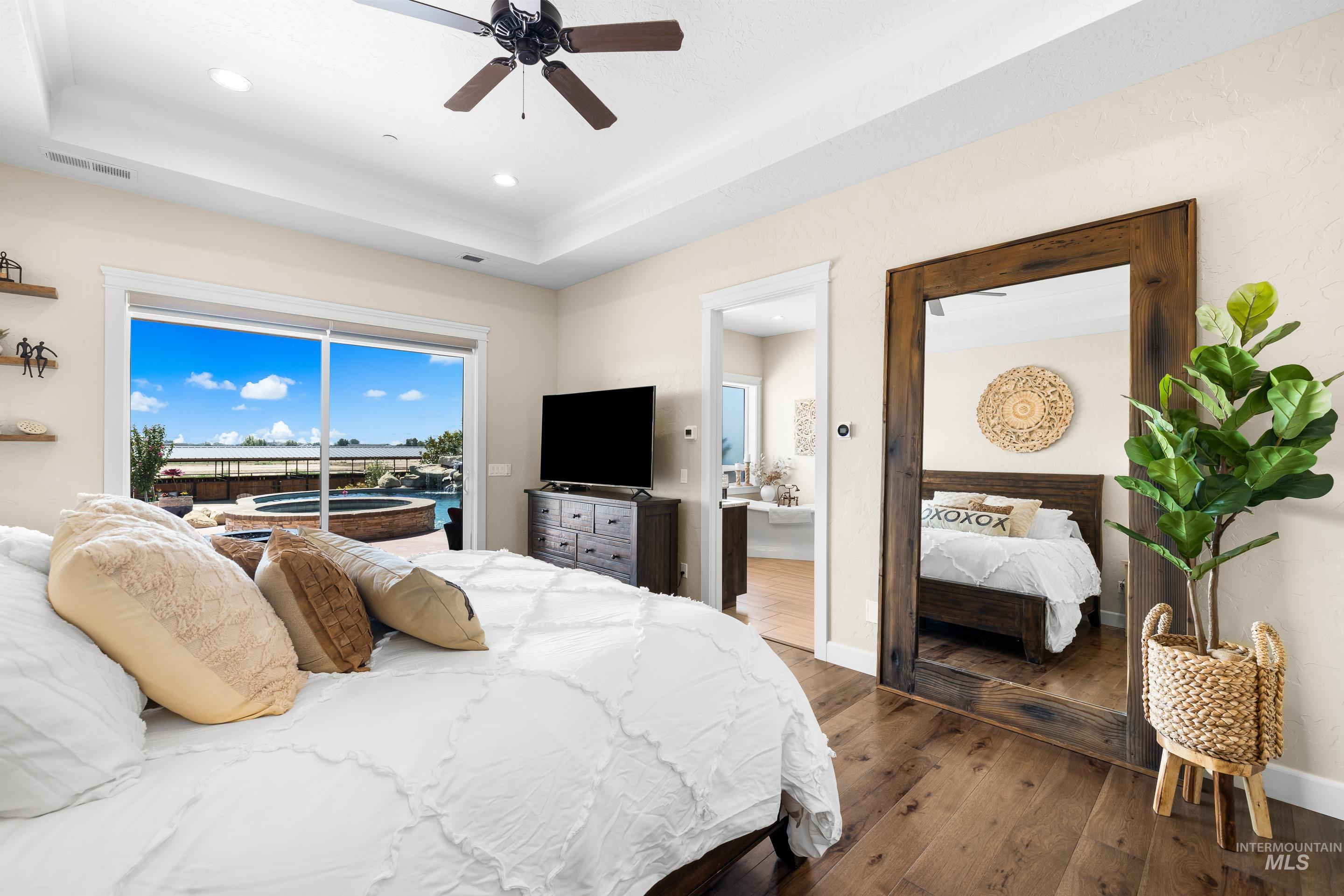 Bedroom featuring hardwood / wood-style flooring, a raised ceiling, access to outside, recessed lighting, and a ceiling fan