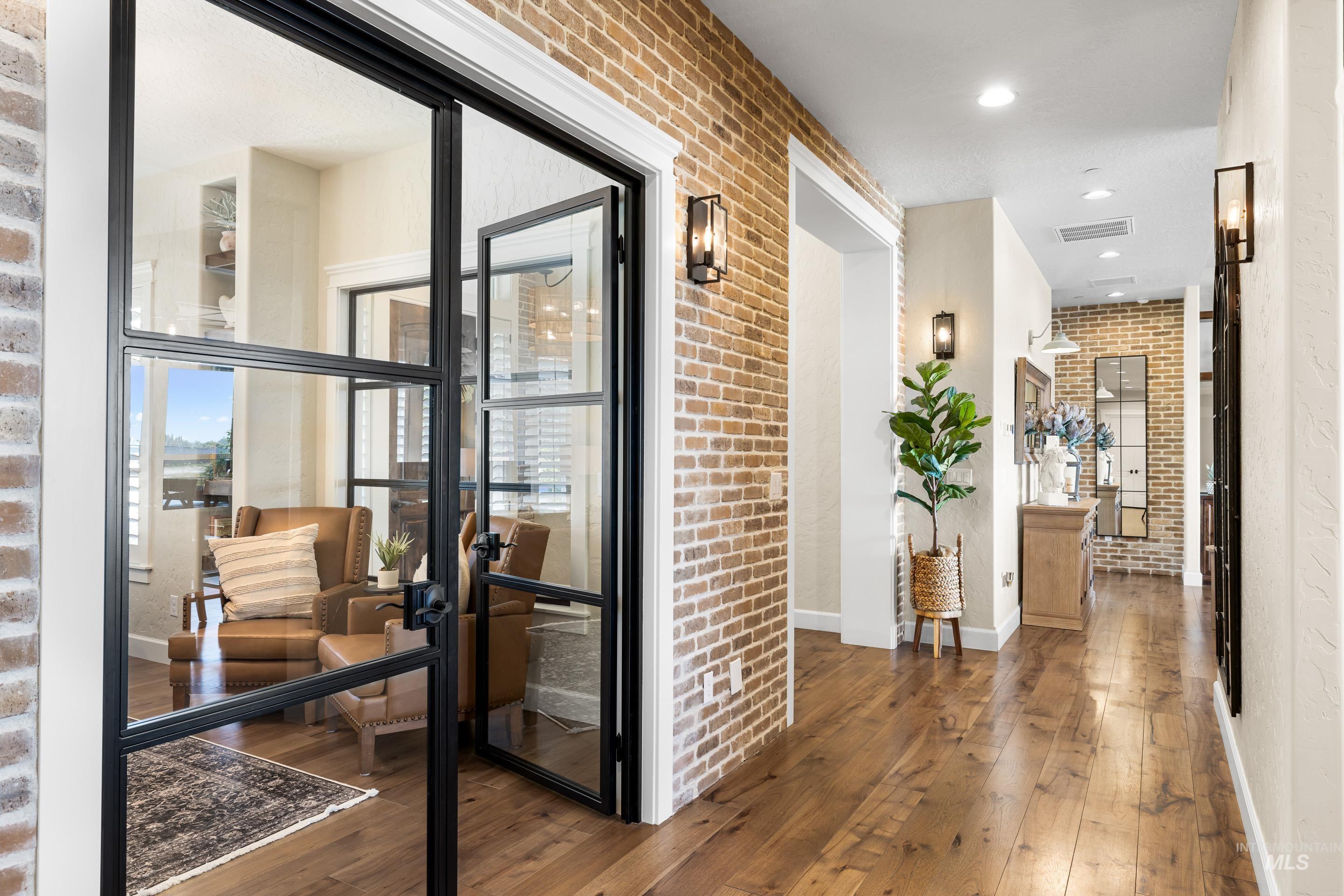 Corridor featuring brick wall, hardwood / wood-style flooring, and recessed lighting