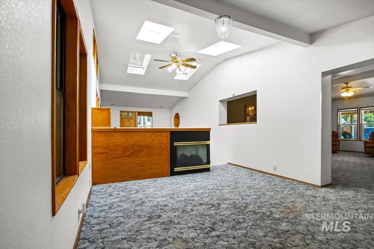 Bonus room featuring ceiling fan, carpet, a skylight, and a multi sided fireplace