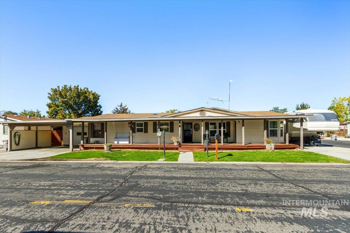 Ranch-style house featuring covered porch, concrete driveway, a front lawn, and an attached carport
