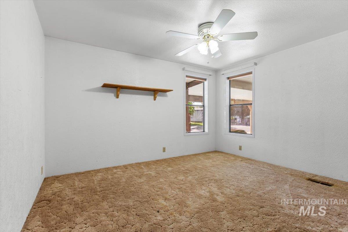 Carpeted empty room featuring ceiling fan, a textured ceiling, and a textured wall