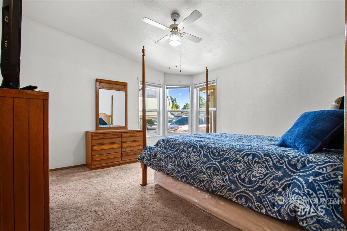Bedroom with access to outside, carpet flooring, vaulted ceiling, a ceiling fan, and a textured ceiling