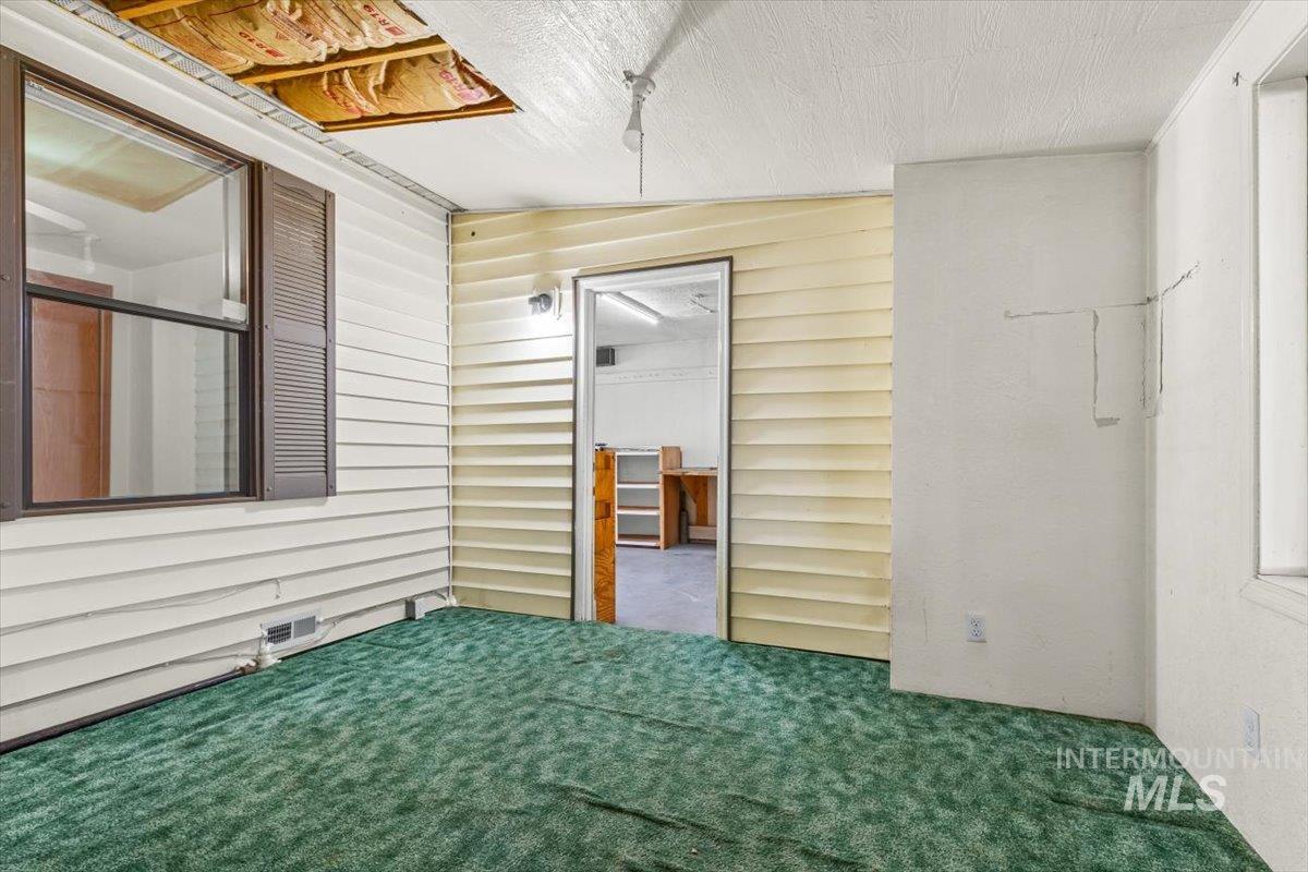 Unfurnished bedroom with wood walls, carpet floors, and vaulted ceiling