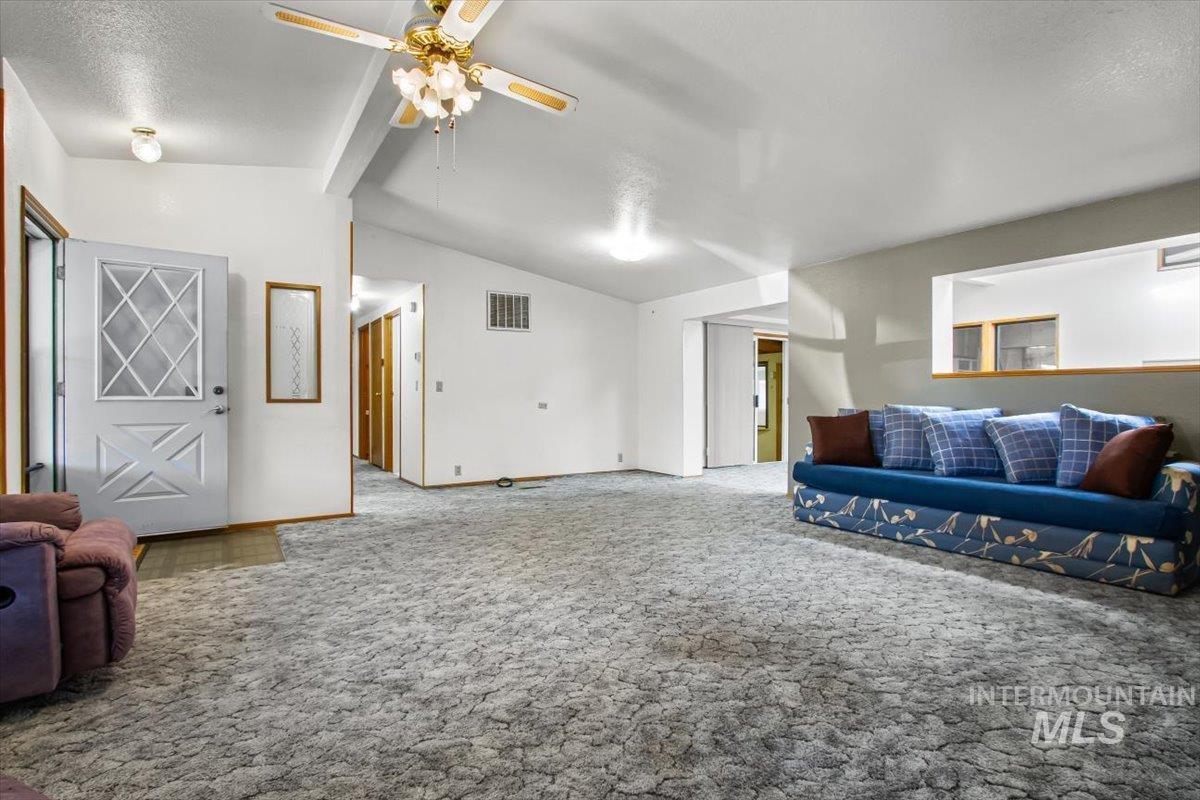 Carpeted living area with a ceiling fan and a textured ceiling