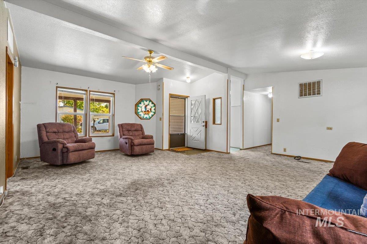 Sitting room with a textured ceiling, carpet floors, and a ceiling fan