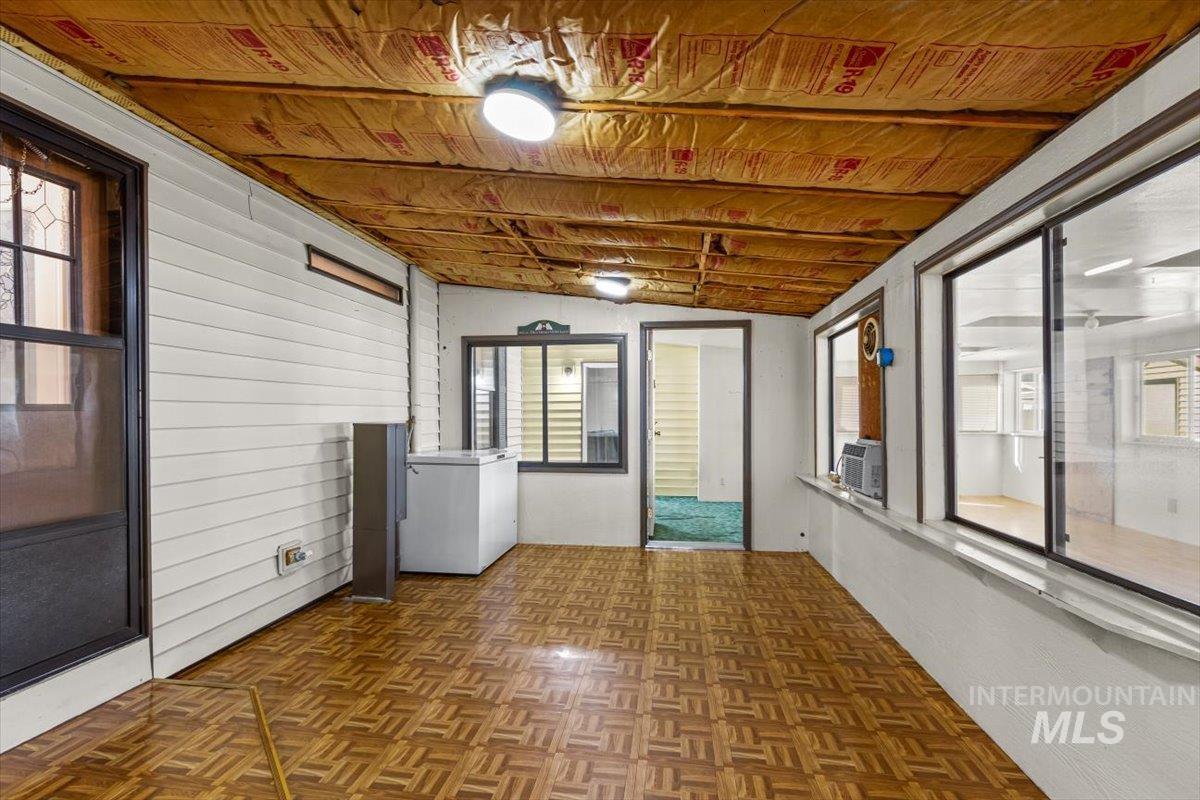 Unfurnished sunroom with healthy amount of natural light, lofted ceiling, and cooling unit