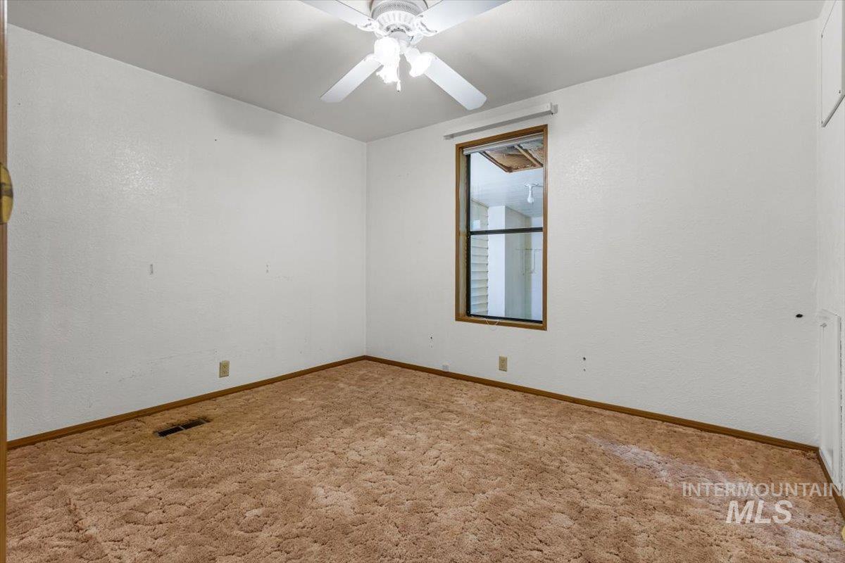 Carpeted empty room featuring a textured wall and ceiling fan