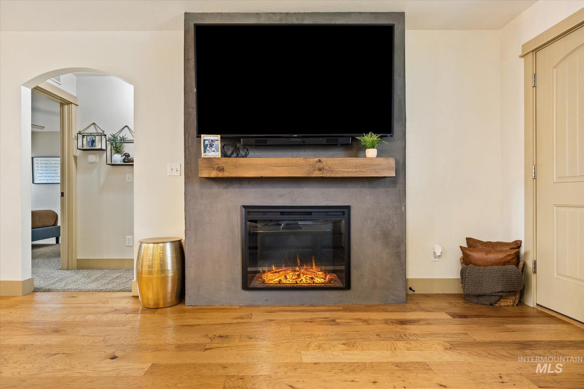 Detailed view of wood finished floors, arched walkways, and a glass covered fireplace