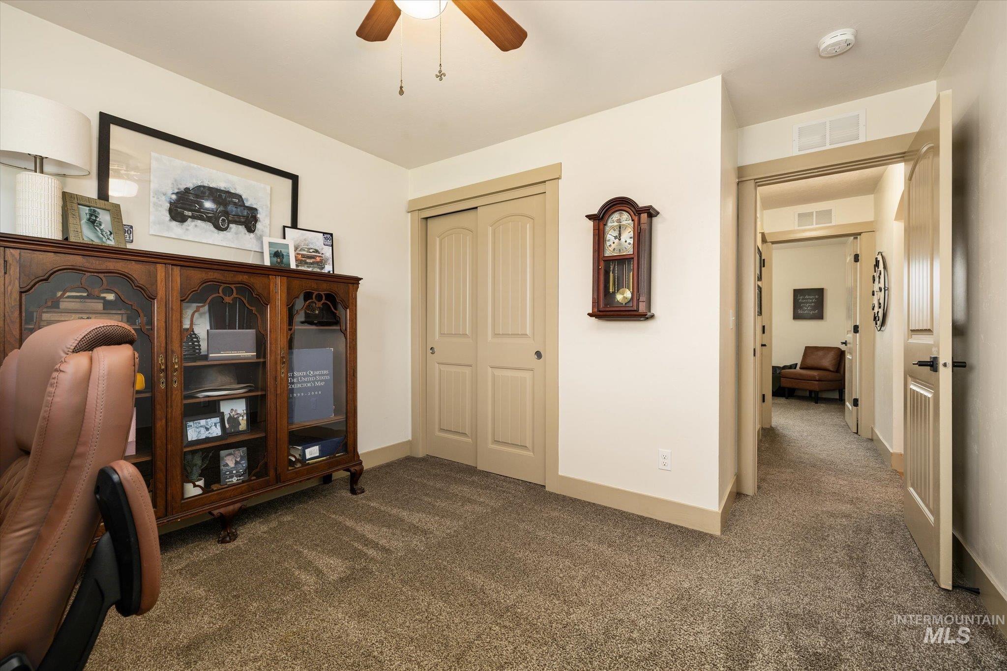 Office area featuring dark colored carpet and a ceiling fan