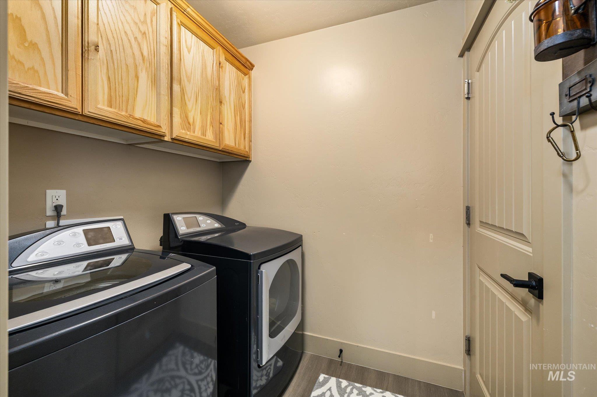 Laundry area featuring cabinet space, dark wood-style flooring, and washer and dryer
