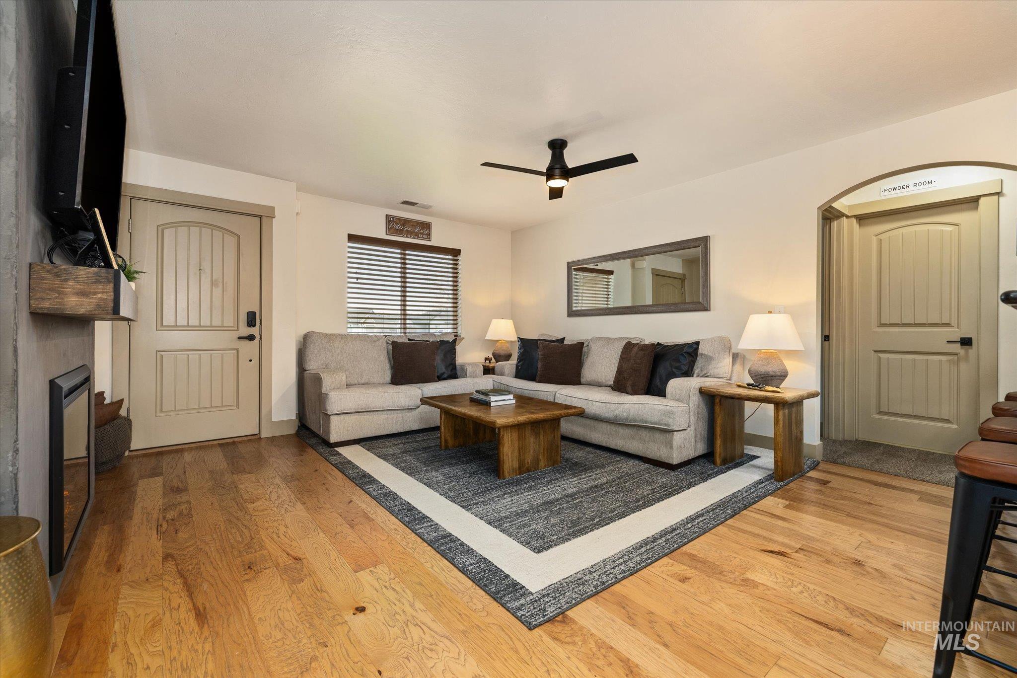 Living room featuring light wood-style floors, a ceiling fan, and a fireplace