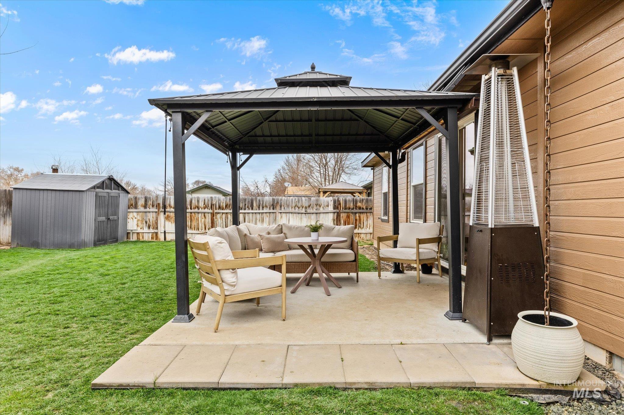 Fenced backyard with an outdoor living space, a gazebo, a patio area, and a shed