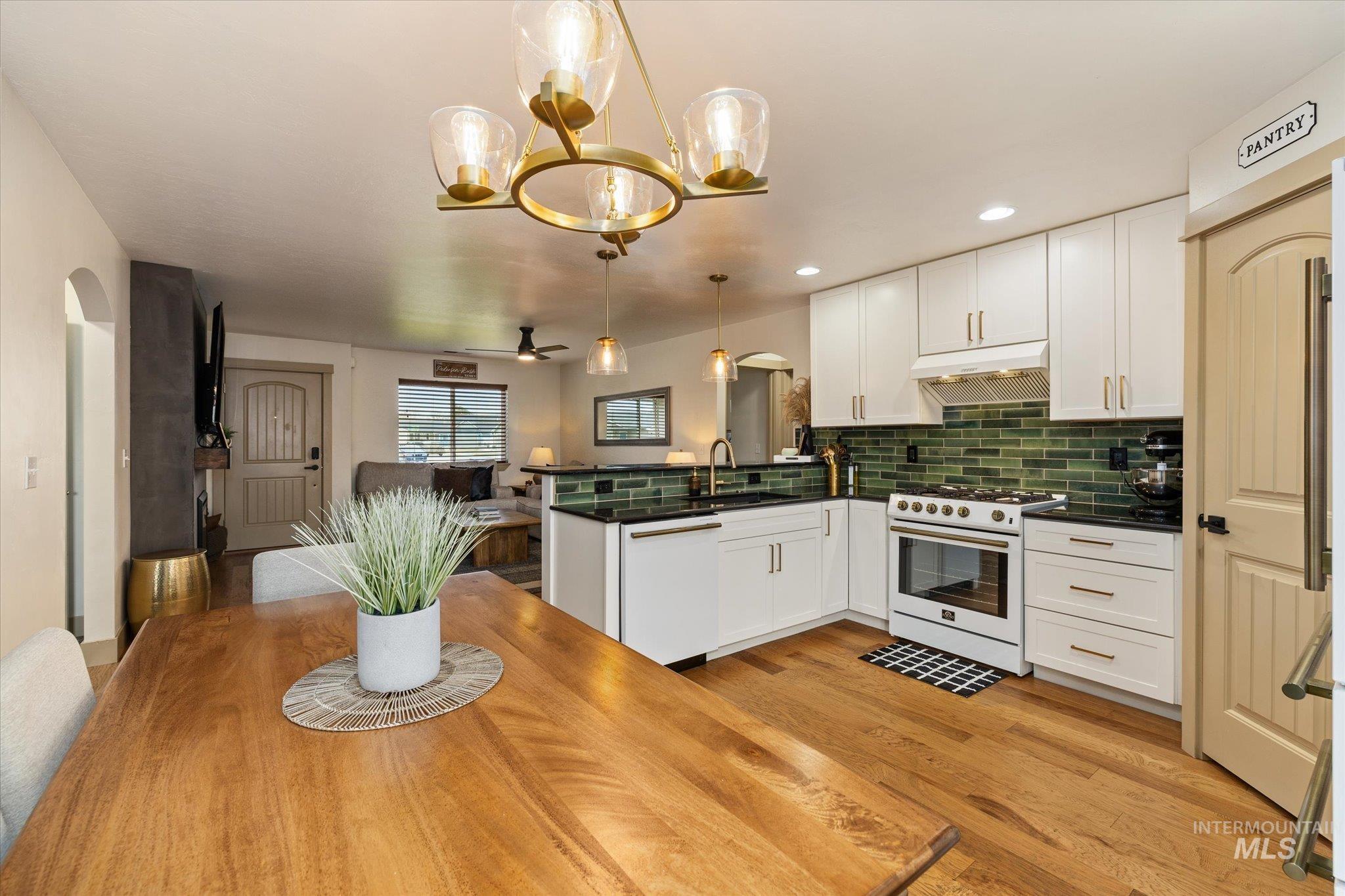 Kitchen with arched walkways, a peninsula, white cabinetry, and range with gas stovetop