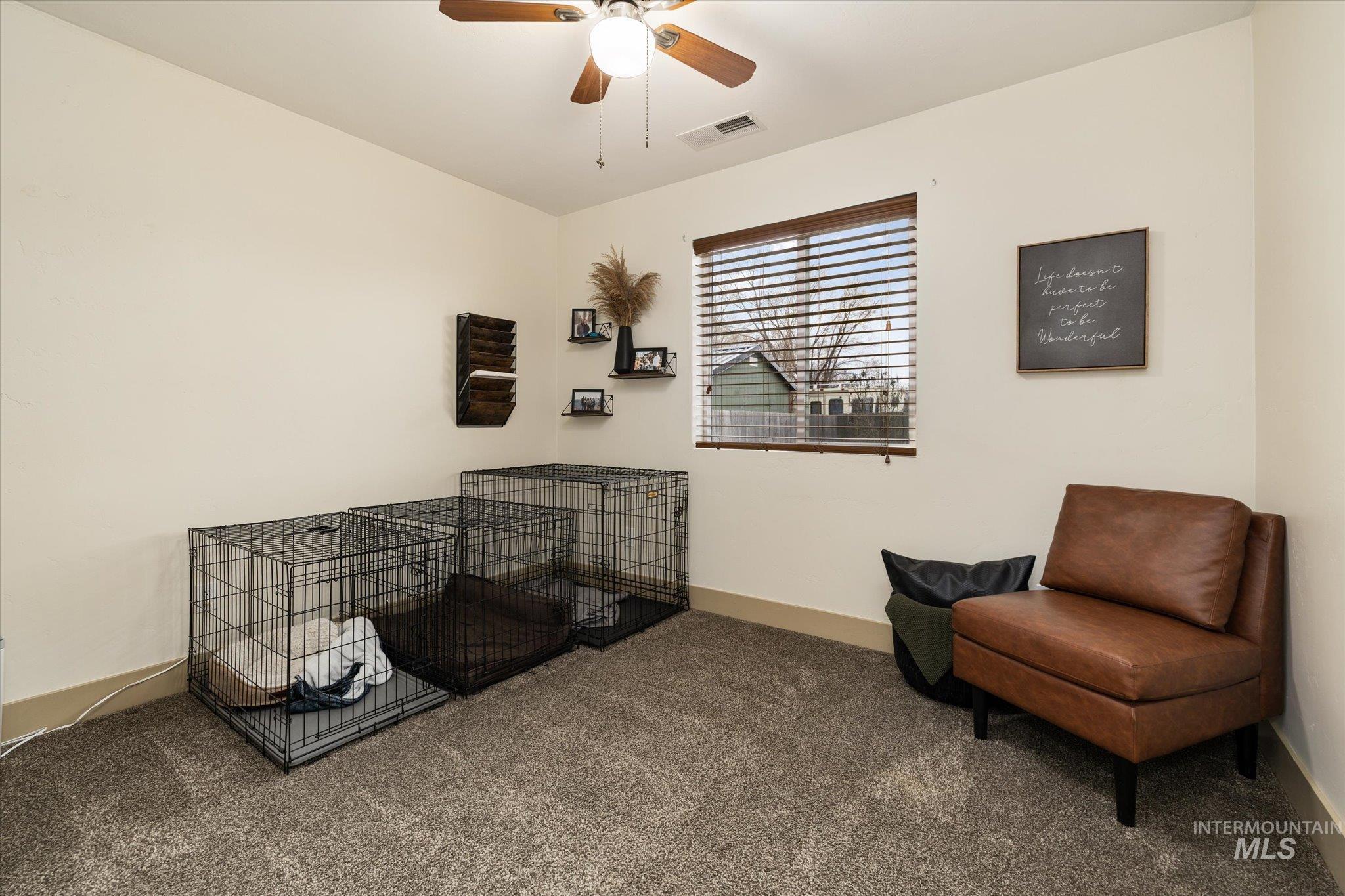 Sitting room with dark carpet and a ceiling fan