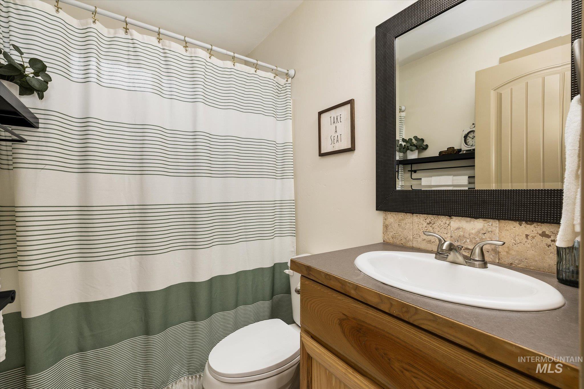 Full bath with vanity, curtained shower, and tasteful backsplash