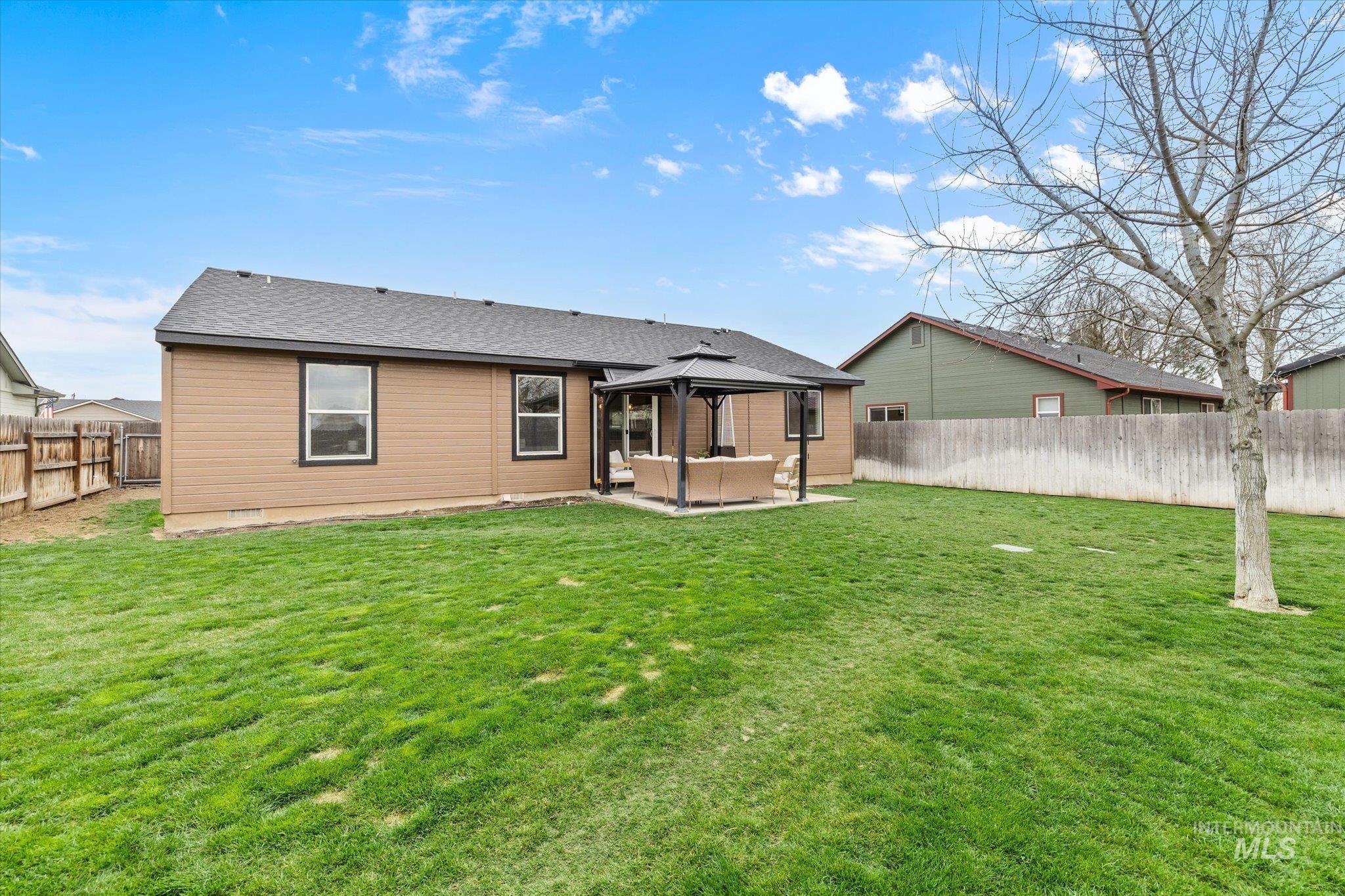 Rear view of property with a patio area, a gazebo, roof with shingles, a fenced backyard, and outdoor furniture