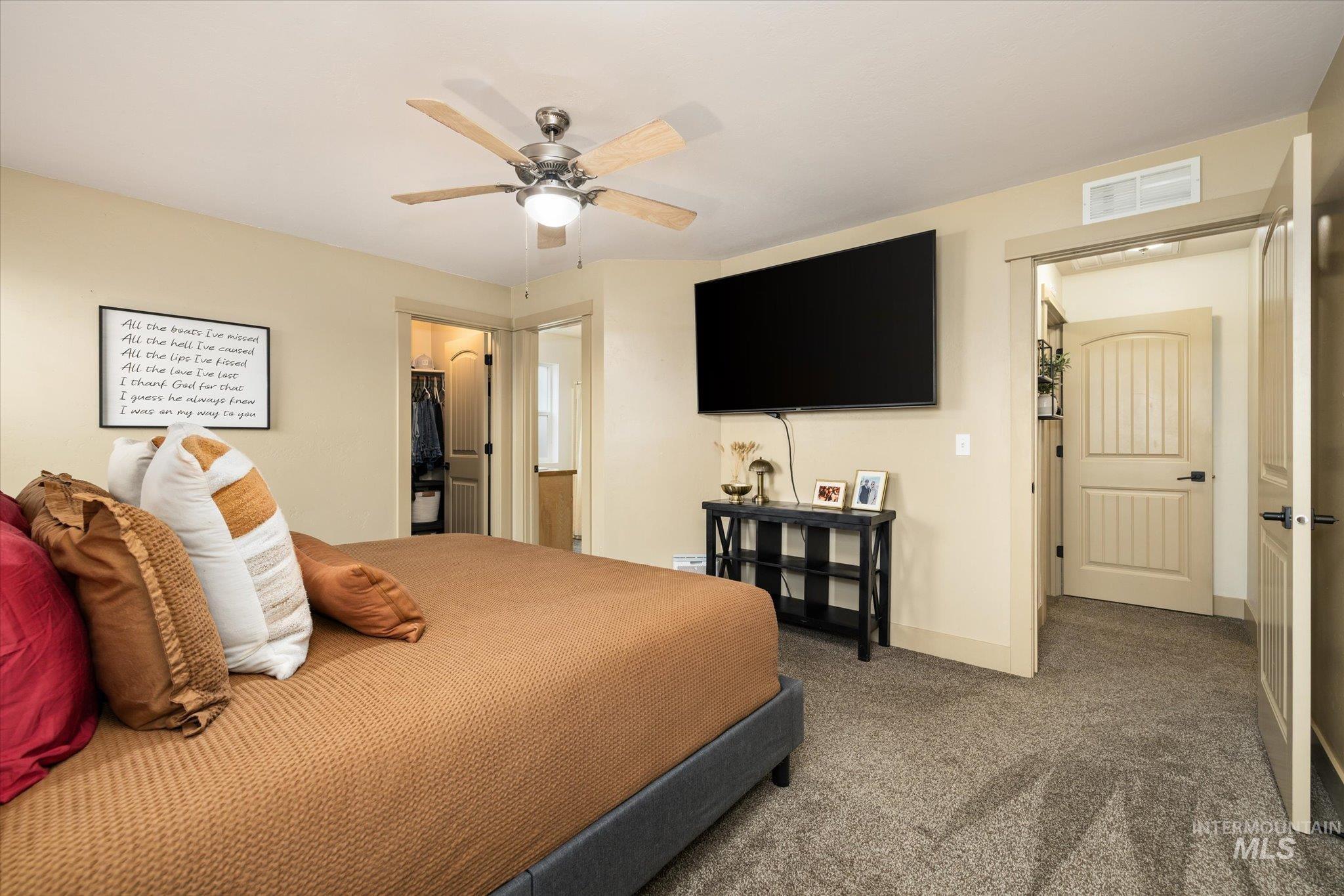 Carpeted bedroom with a walk in closet and a ceiling fan
