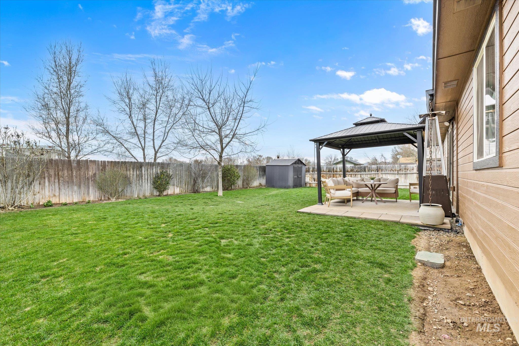 Fenced backyard with a patio area, a gazebo, a storage unit, and an outdoor lounge area
