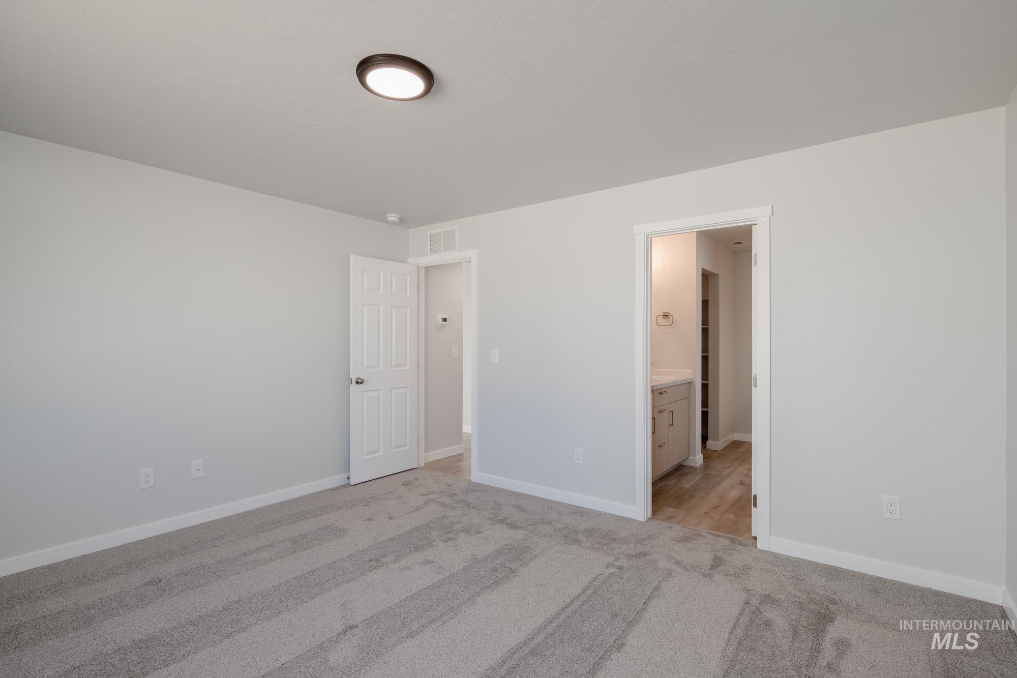 Unfurnished bedroom featuring light carpet and ensuite bathroom