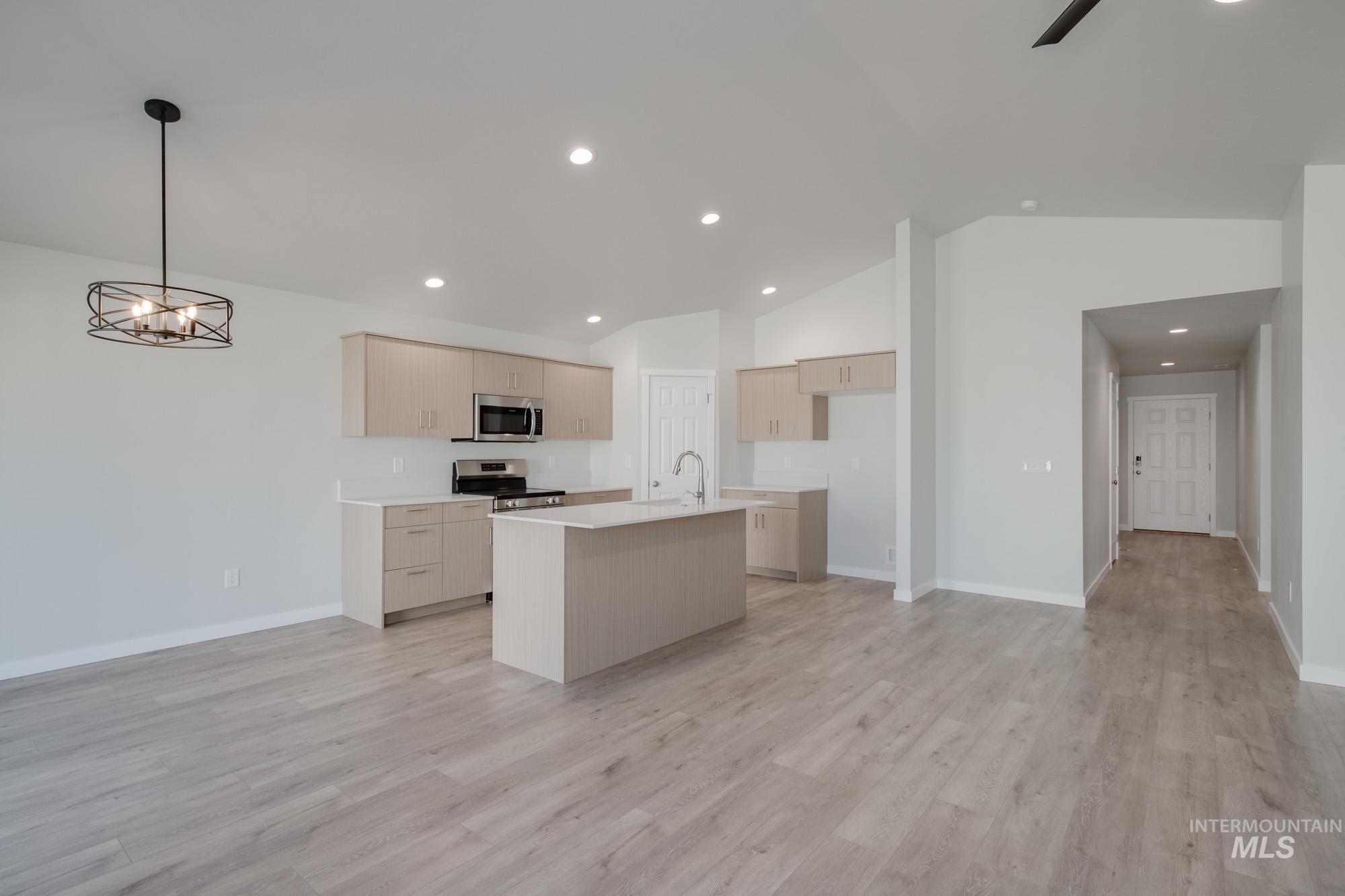 Kitchen featuring stainless steel appliances, an island with sink, hanging light fixtures, light wood finished floors, and recessed lighting