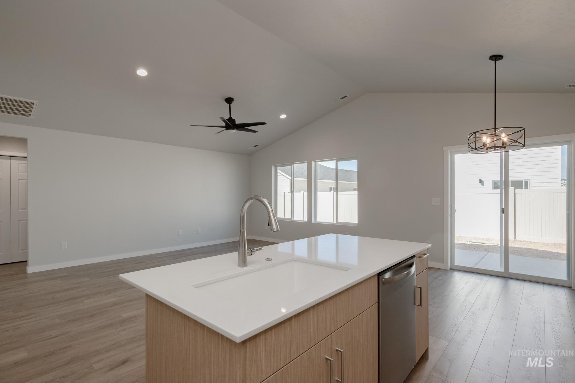Kitchen with recessed lighting, light wood-type flooring, light brown cabinetry, stainless steel dishwasher, and hanging light fixtures